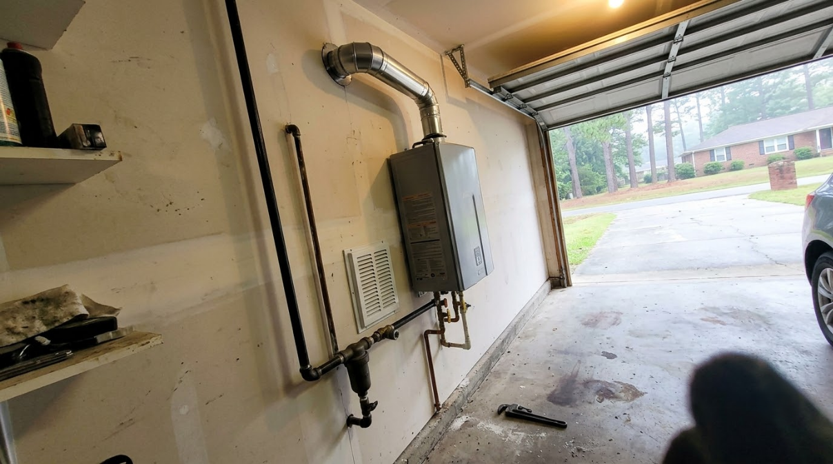 Garage interior with open door, electrical panel on wall, and a car parked outside.