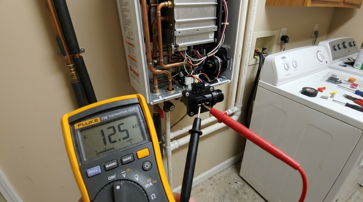 Multimeter testing wires in an open furnace cabinet next to a laundry room washer and dryer