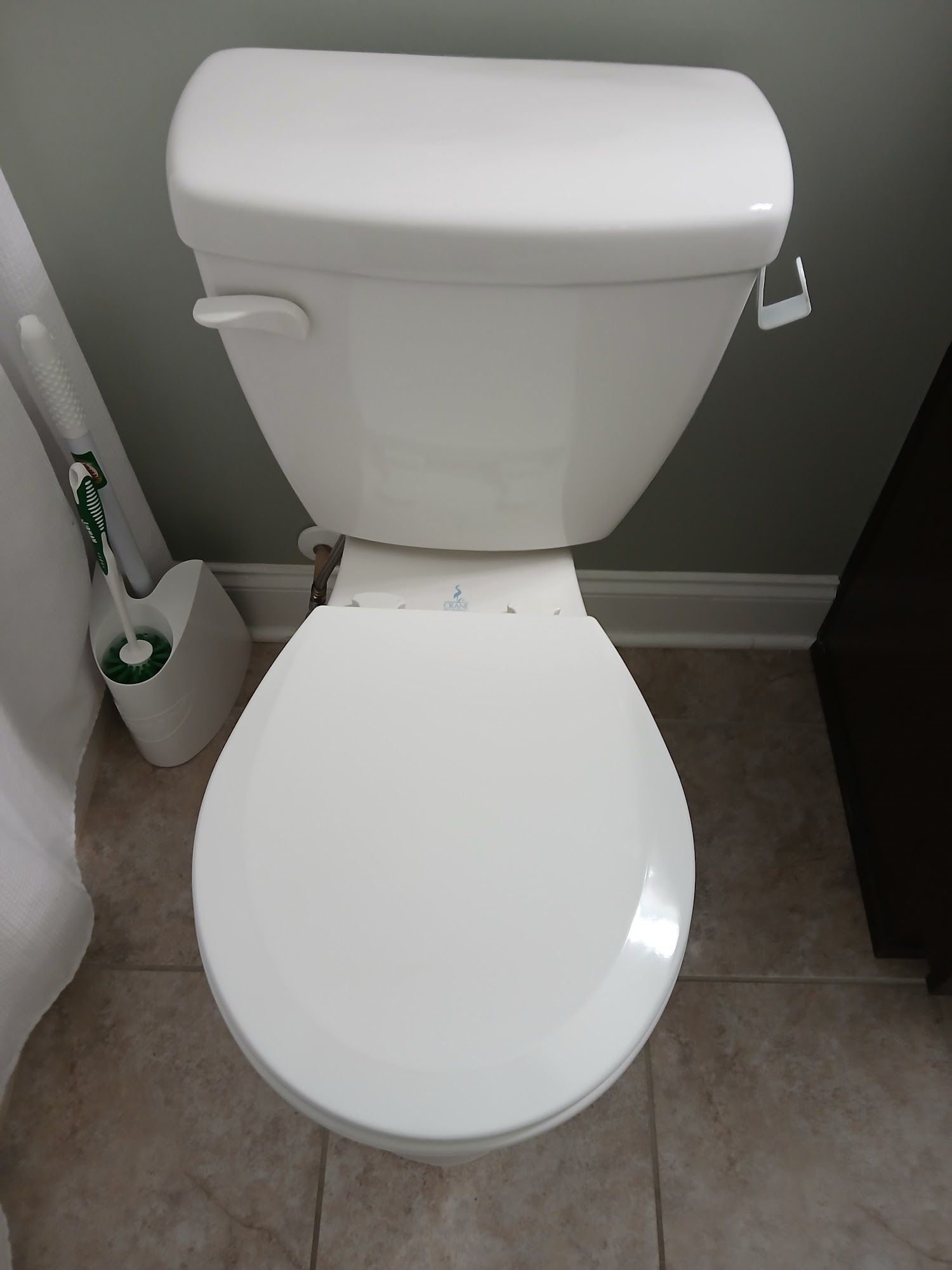 White toilet in a small bathroom with a toilet brush beside it