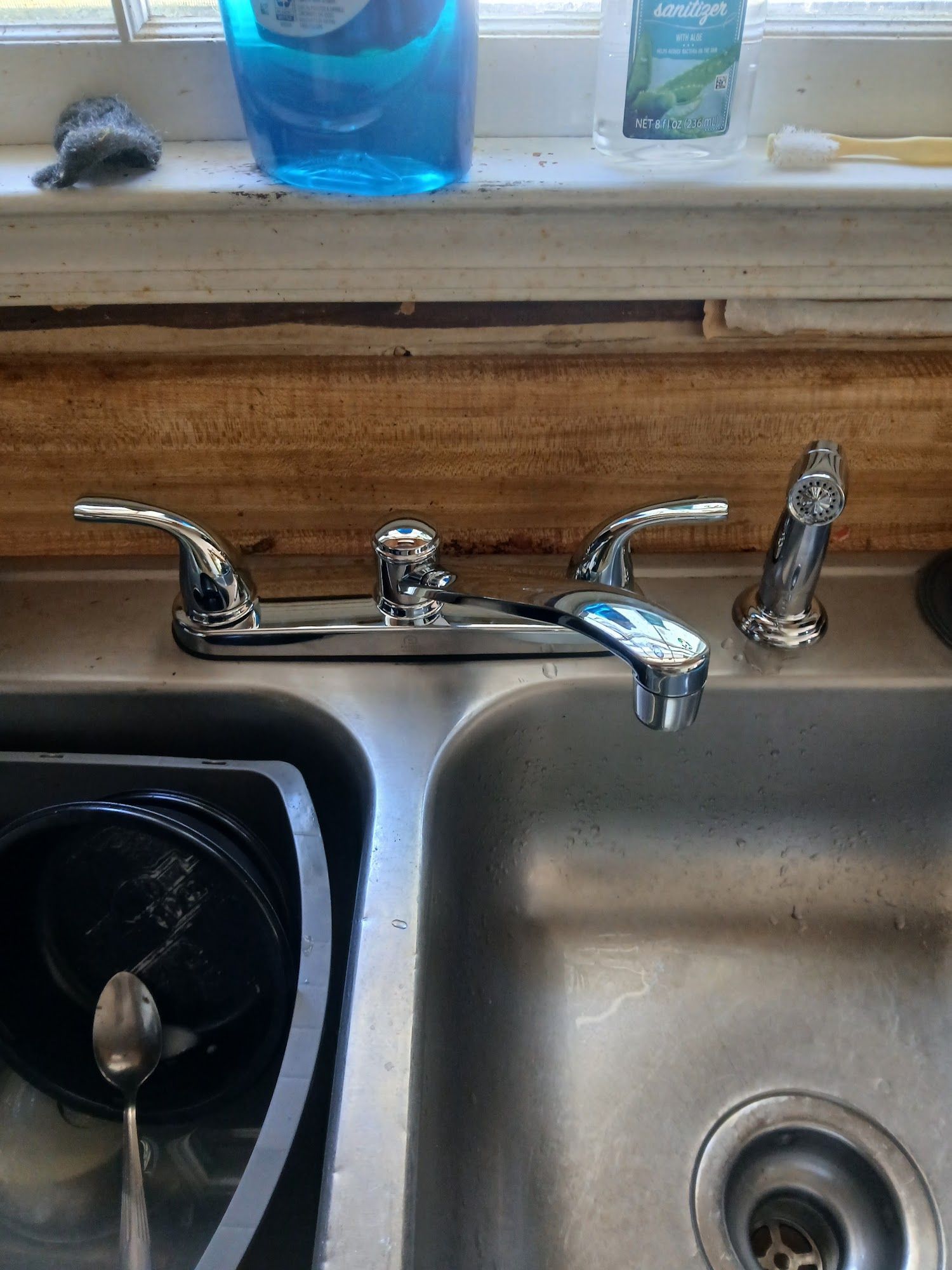 Kitchen sink with chrome faucet, double basins, and a blue soap dispenser on the windowsill.