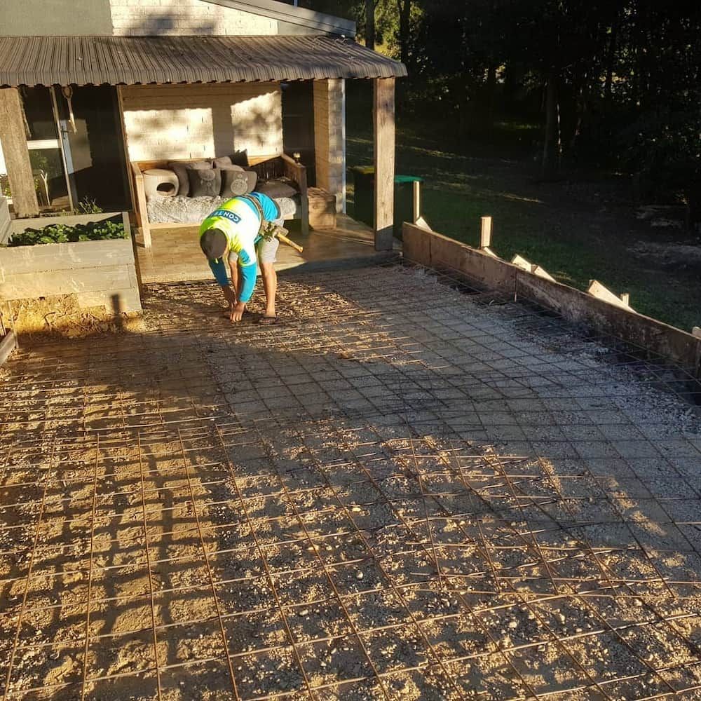 A Man in a Hat is Working on a Concrete Driveway — TJ Concreting in Grafton, NSW
