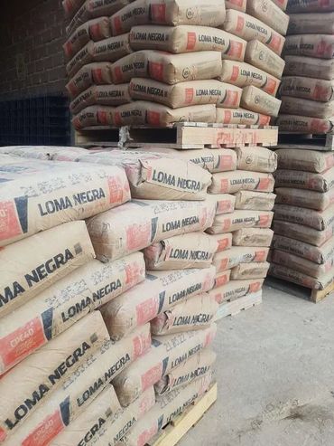 Pilas de sacos de cemento Loma Negra apilados en un almacén o zona de almacenamiento.