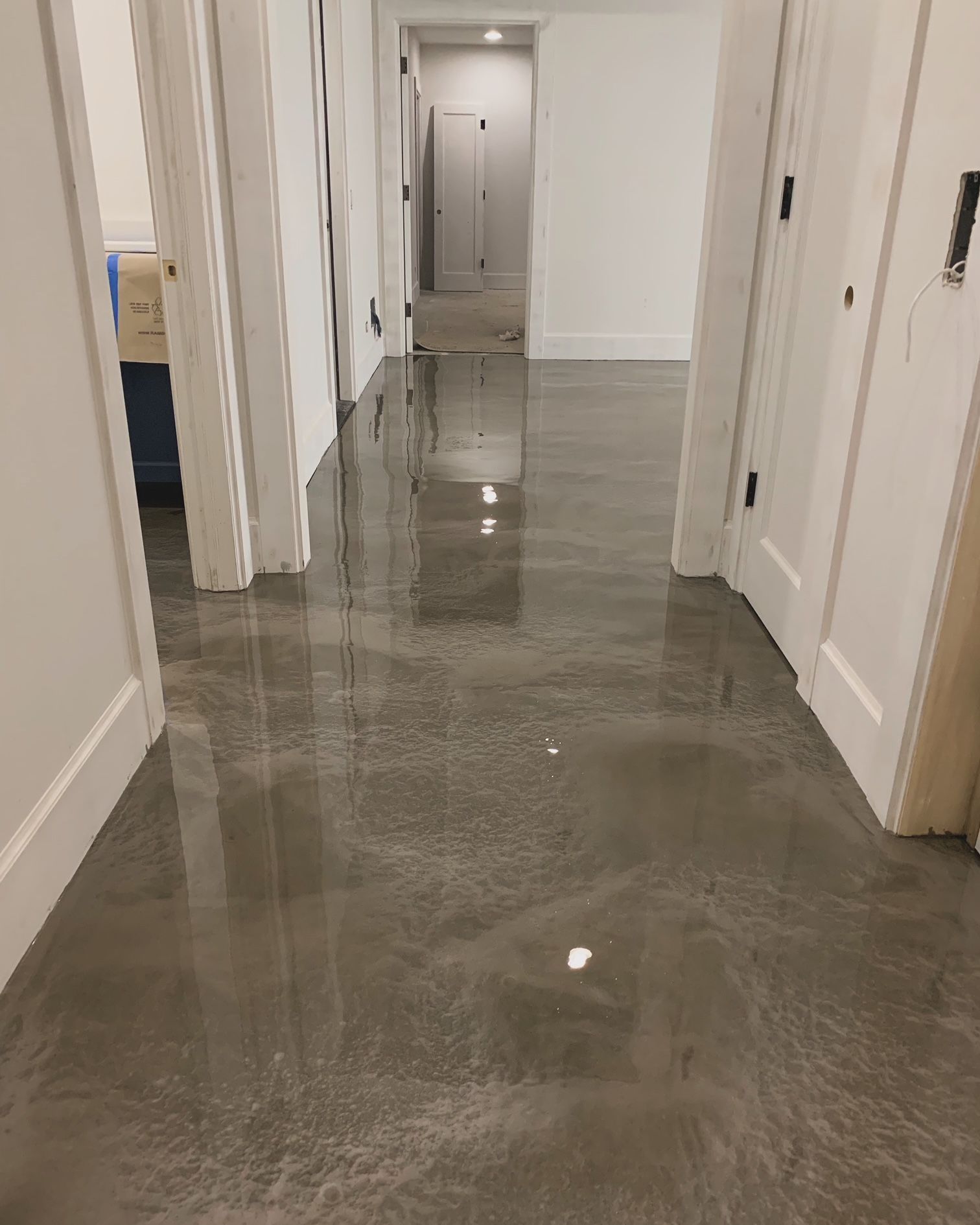 A hallway with a shiny metallic floor and white doors.