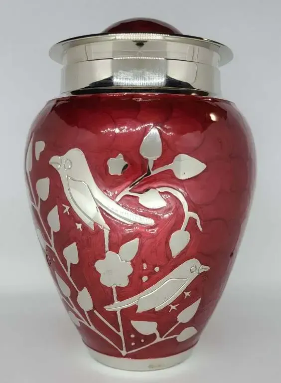 A red vase with silver birds and leaves on it