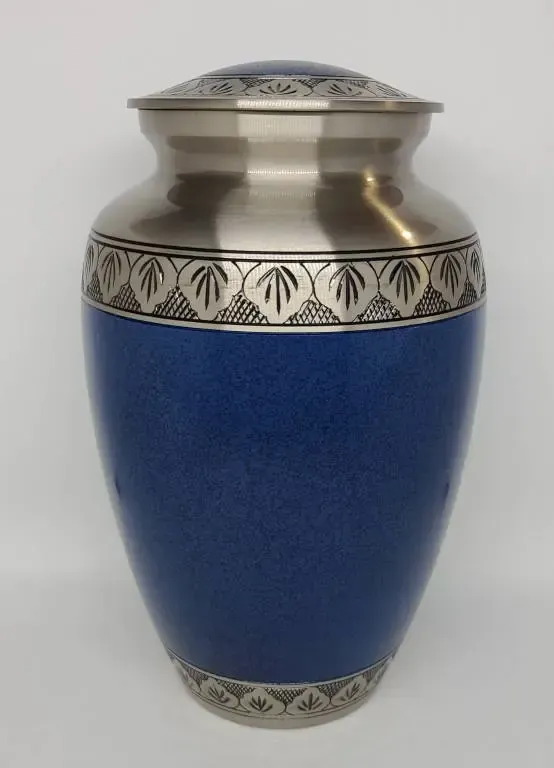 A blue urn with a silver border and leaves on it is sitting on a white surface.