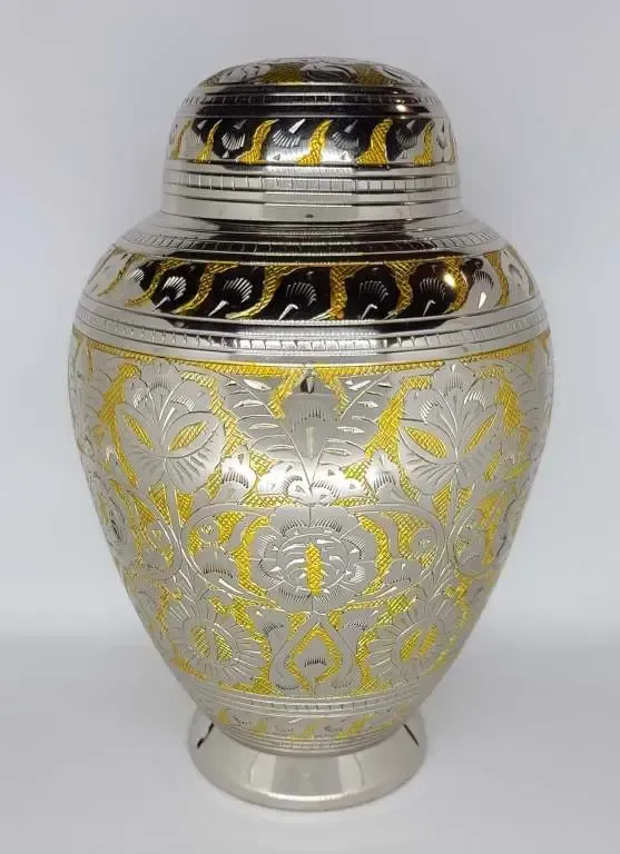 A silver and gold vase with a lid is sitting on a table.