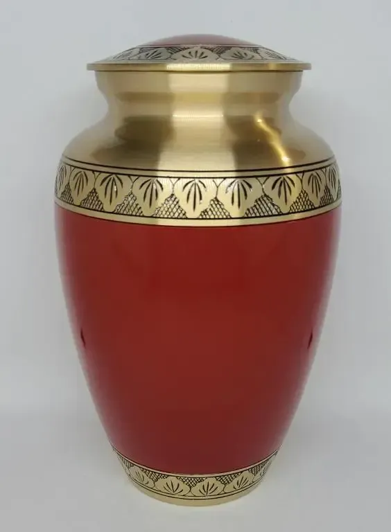 A red and gold urn is sitting on a white surface.
