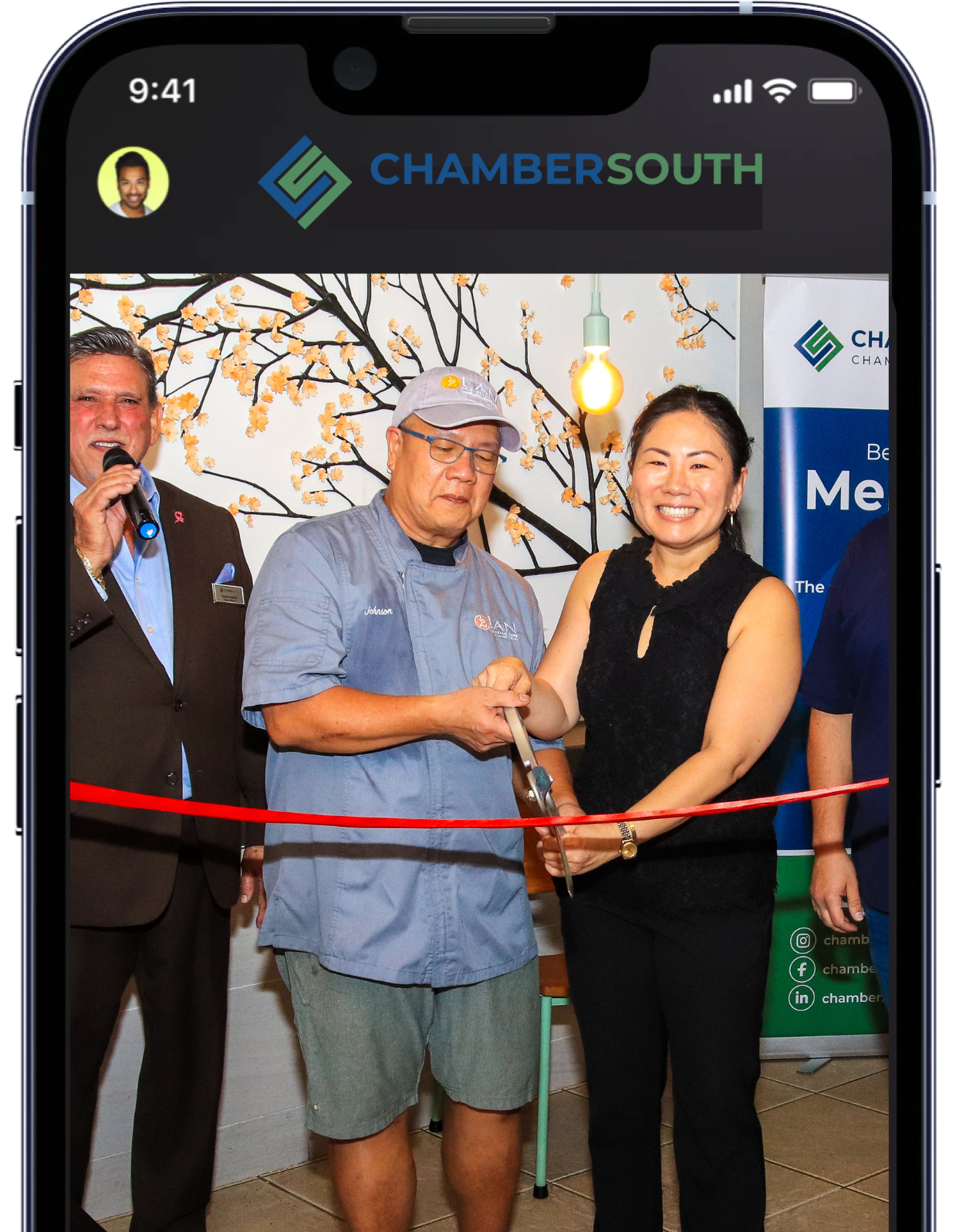 A group of people are cutting a red ribbon on a phone screen that says chambersouth