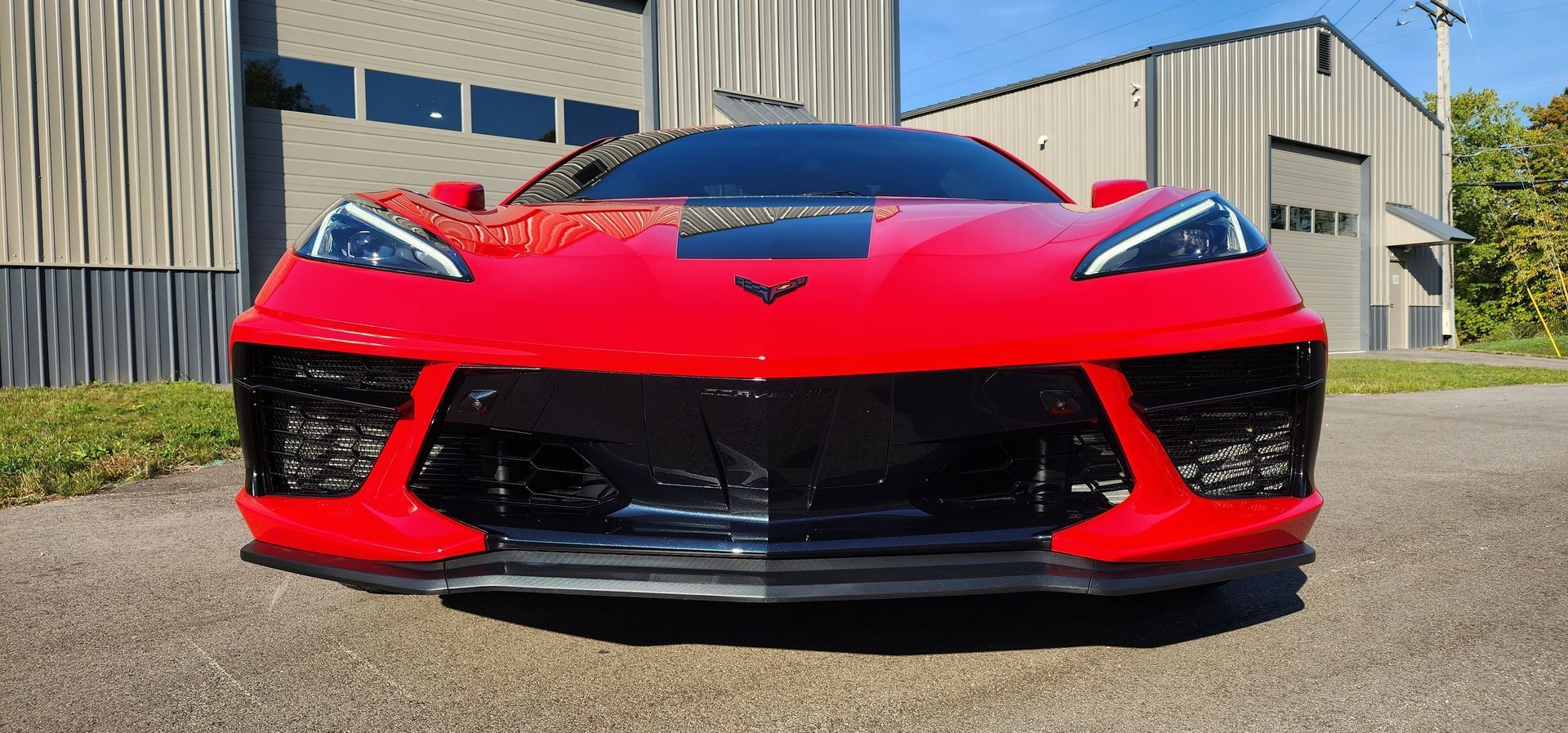 Front view of a red sports car parked outside an industrial building