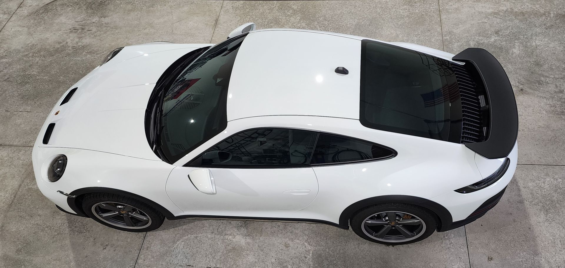 White sports car viewed from above on a concrete surface