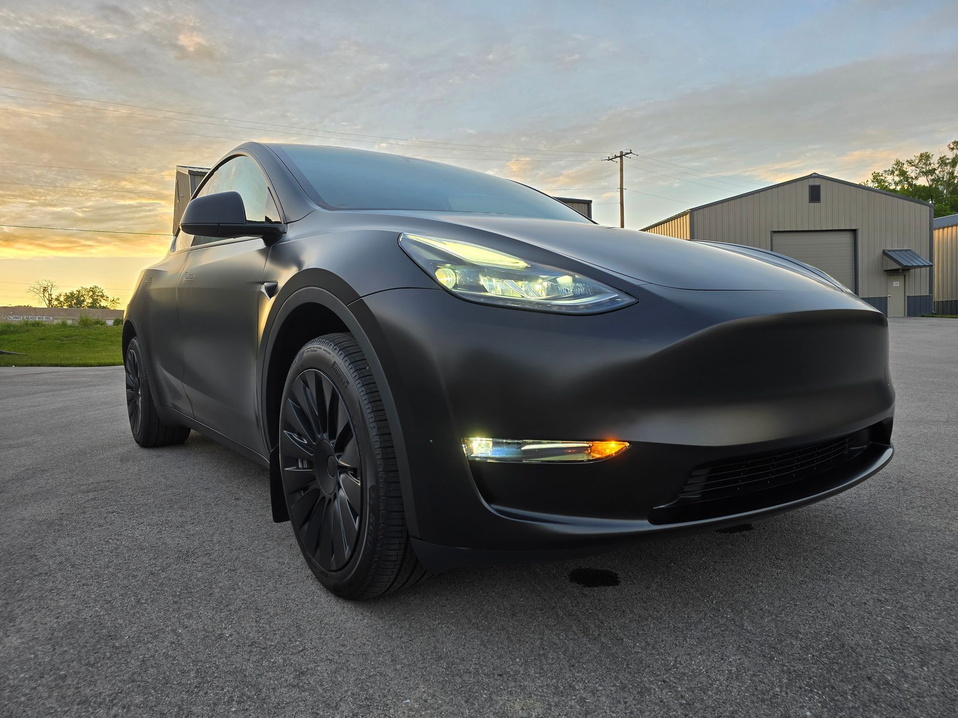 Black Tesla sedan parked on a street at sunset, front view