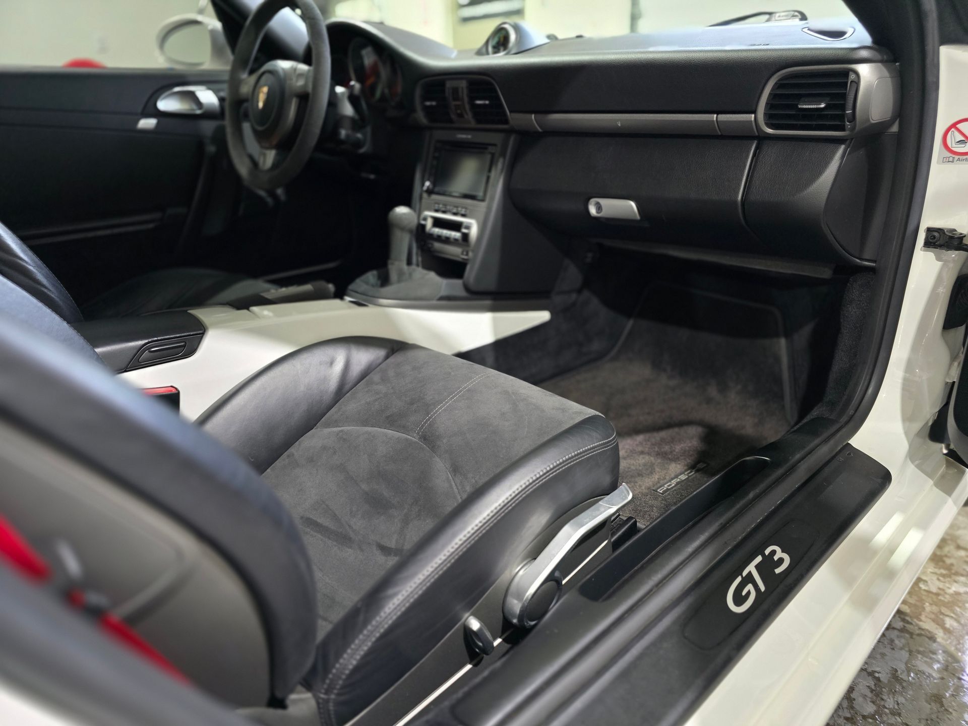 Interior of a Porsche GT3, showing the front passenger seat and dashboard with black and gray trim.
