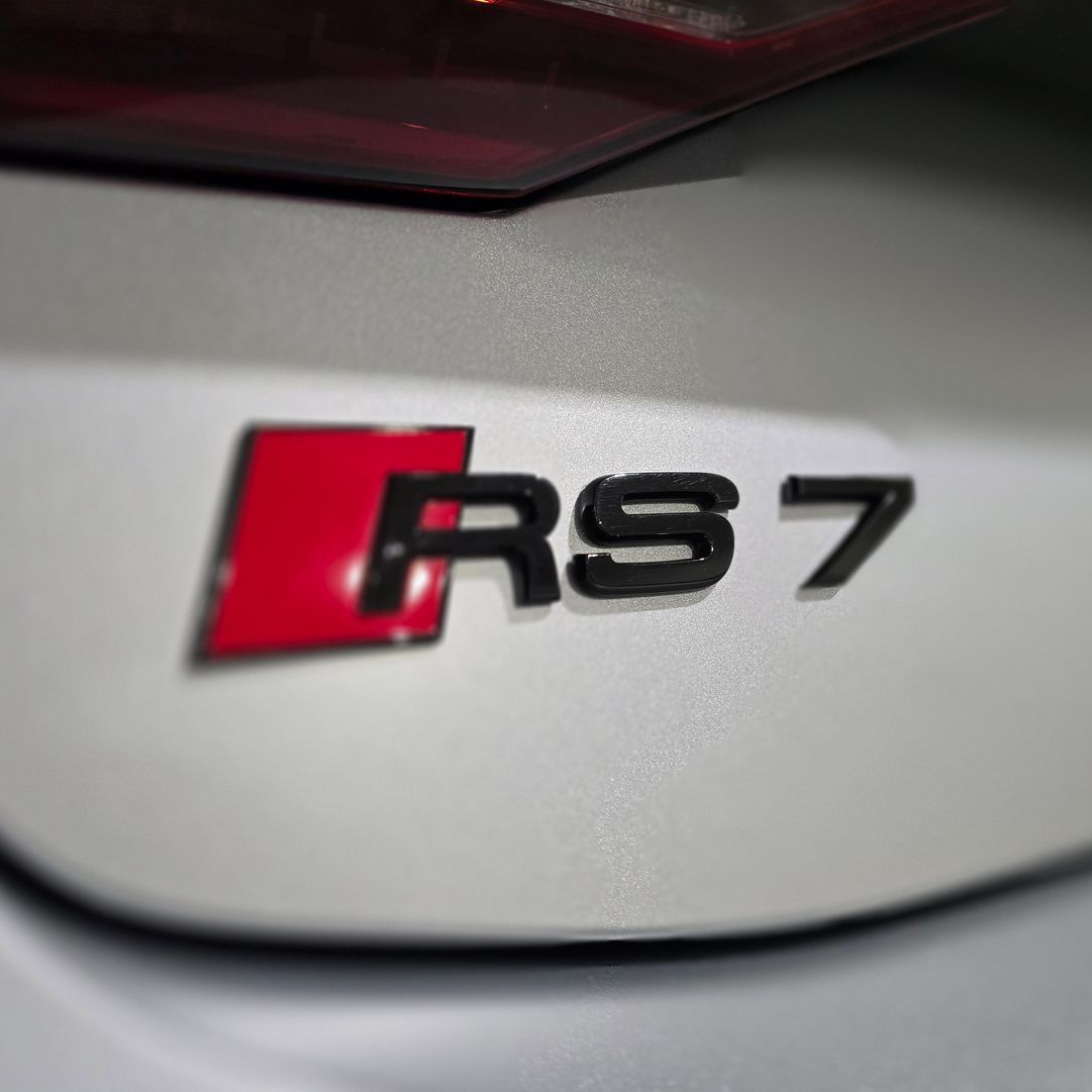Close-up of a sleek black car’s rear taillight with red and white LED accents
