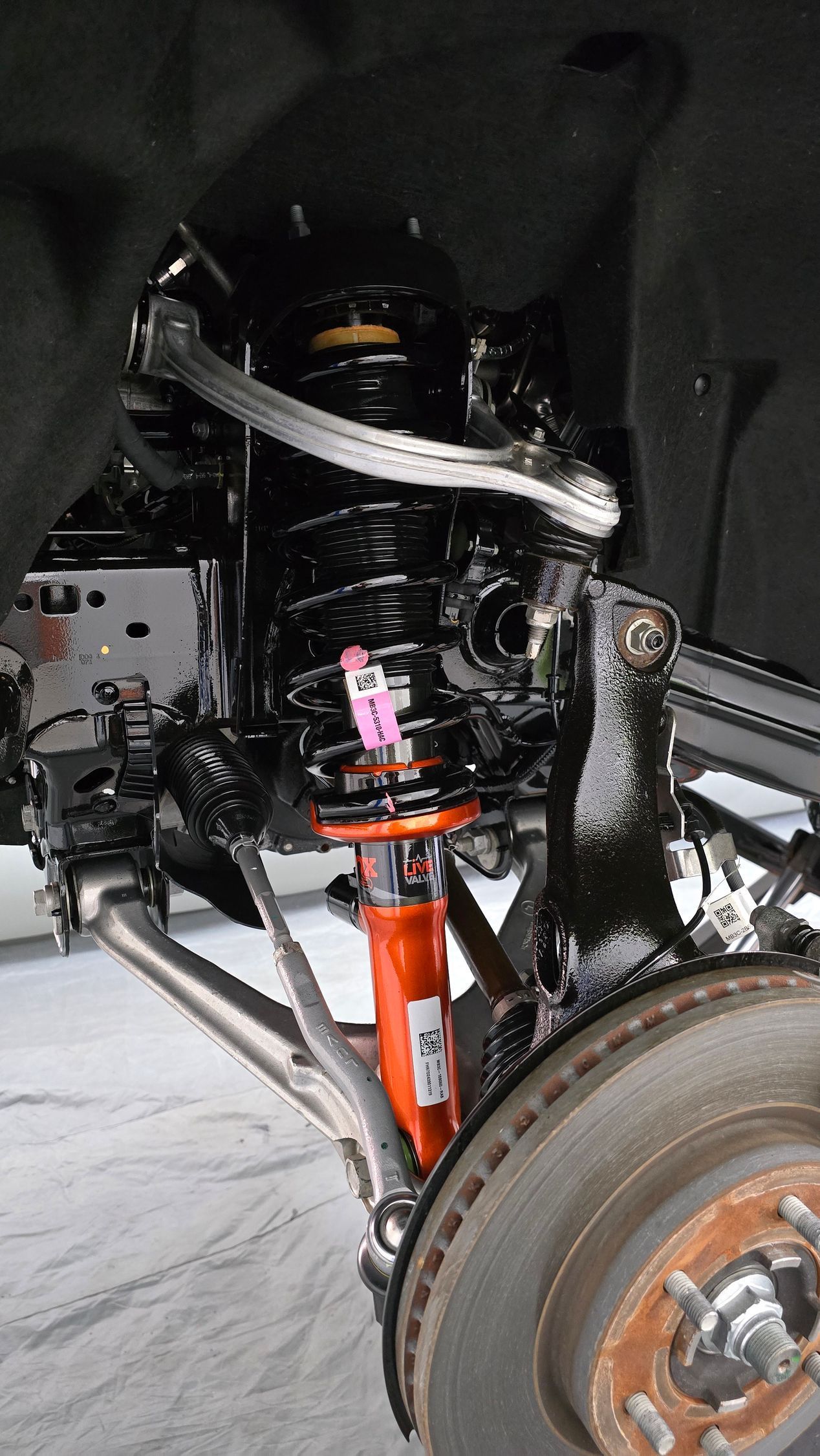Hand polishing a white car’s red tail light with a buffer pad