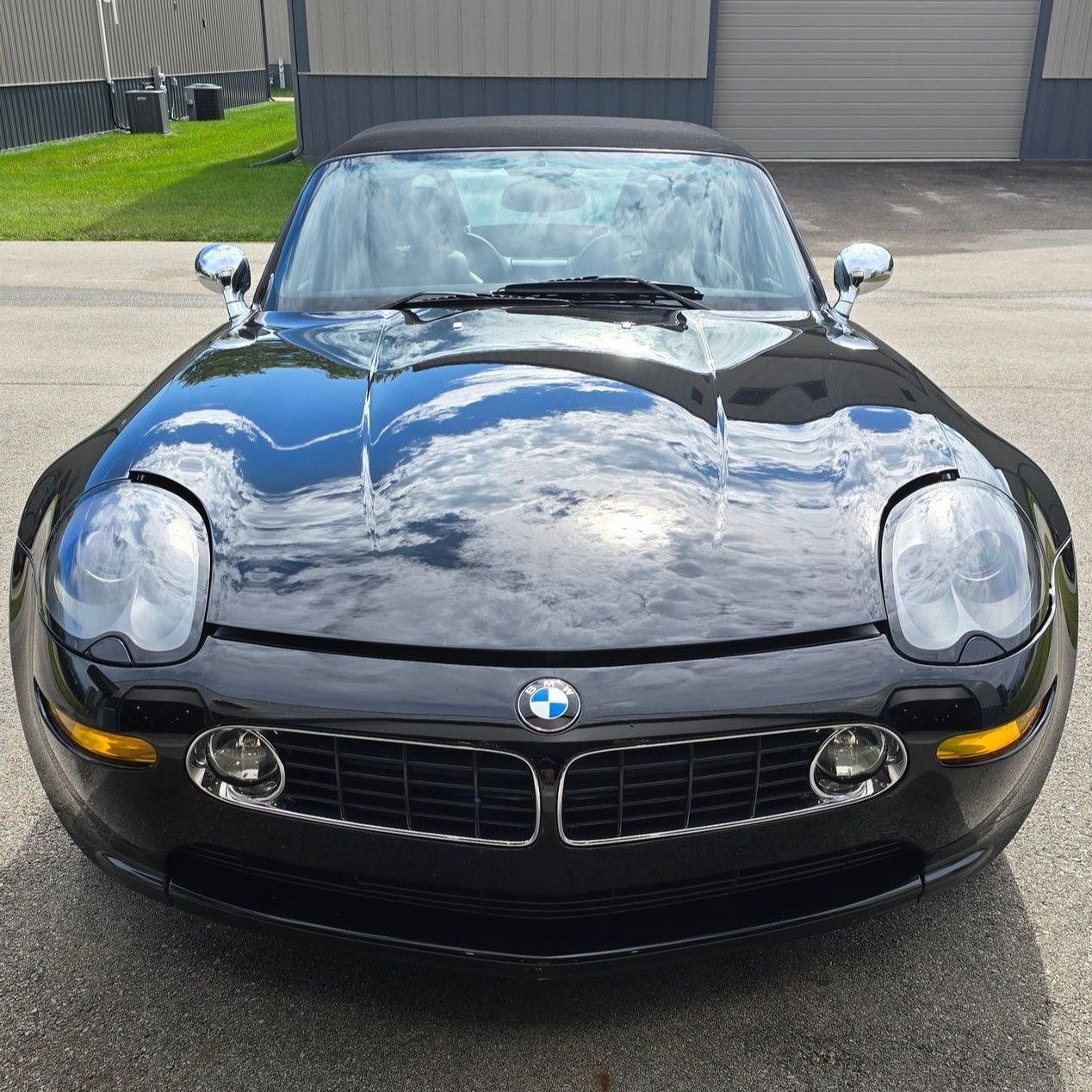 Black BMW sports car parked on pavement, front view, with reflective hood and round headlights
