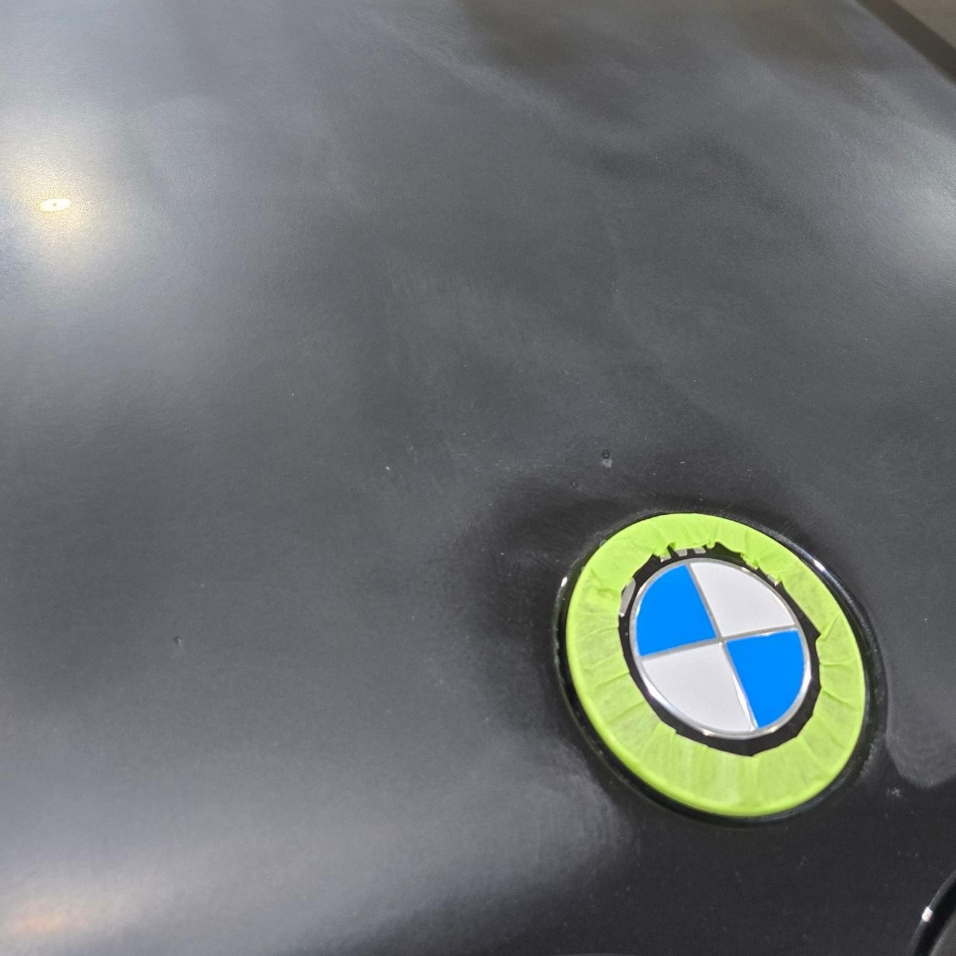 Hand polishing a black car door with a rotary buffer and foam pad