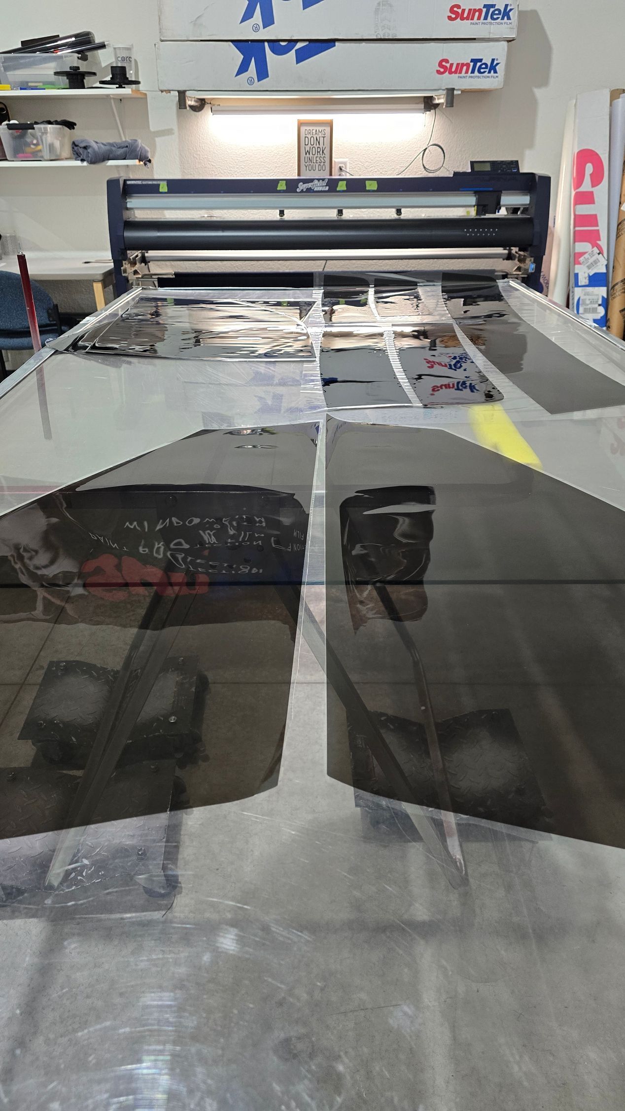 Large-format printer printing a black-and-white graphic on glossy vinyl in a workshop