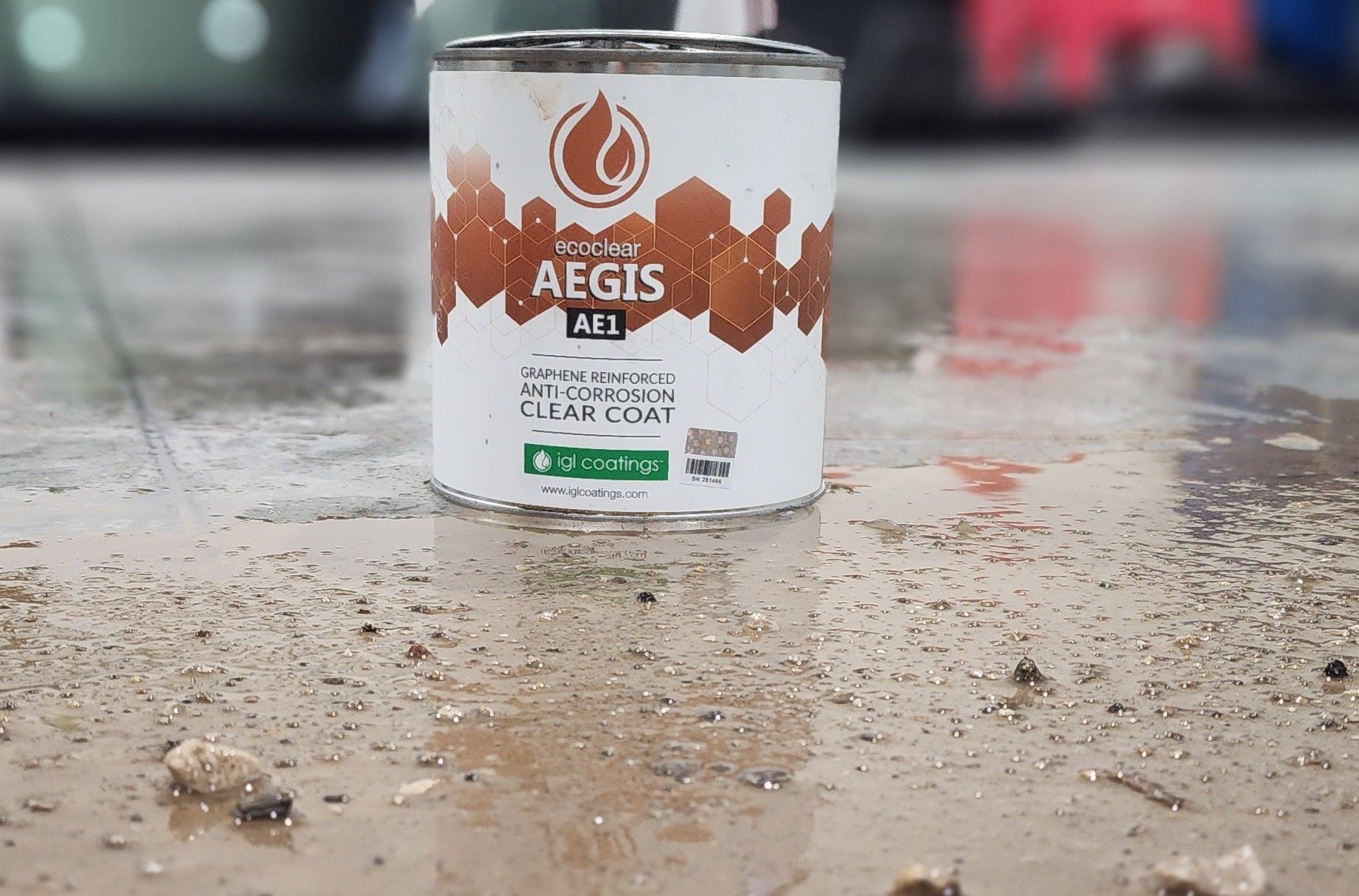 White Aegis Seal paint can on wet concrete with blurred tools in the background