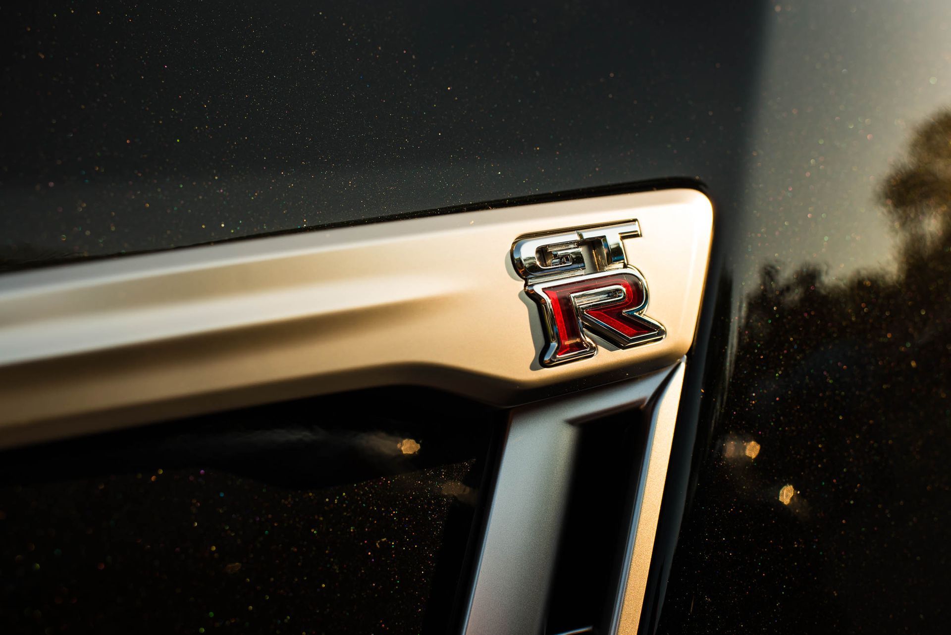 Close-up of a car grille with a red and chrome GT-R badge on a black surface.
