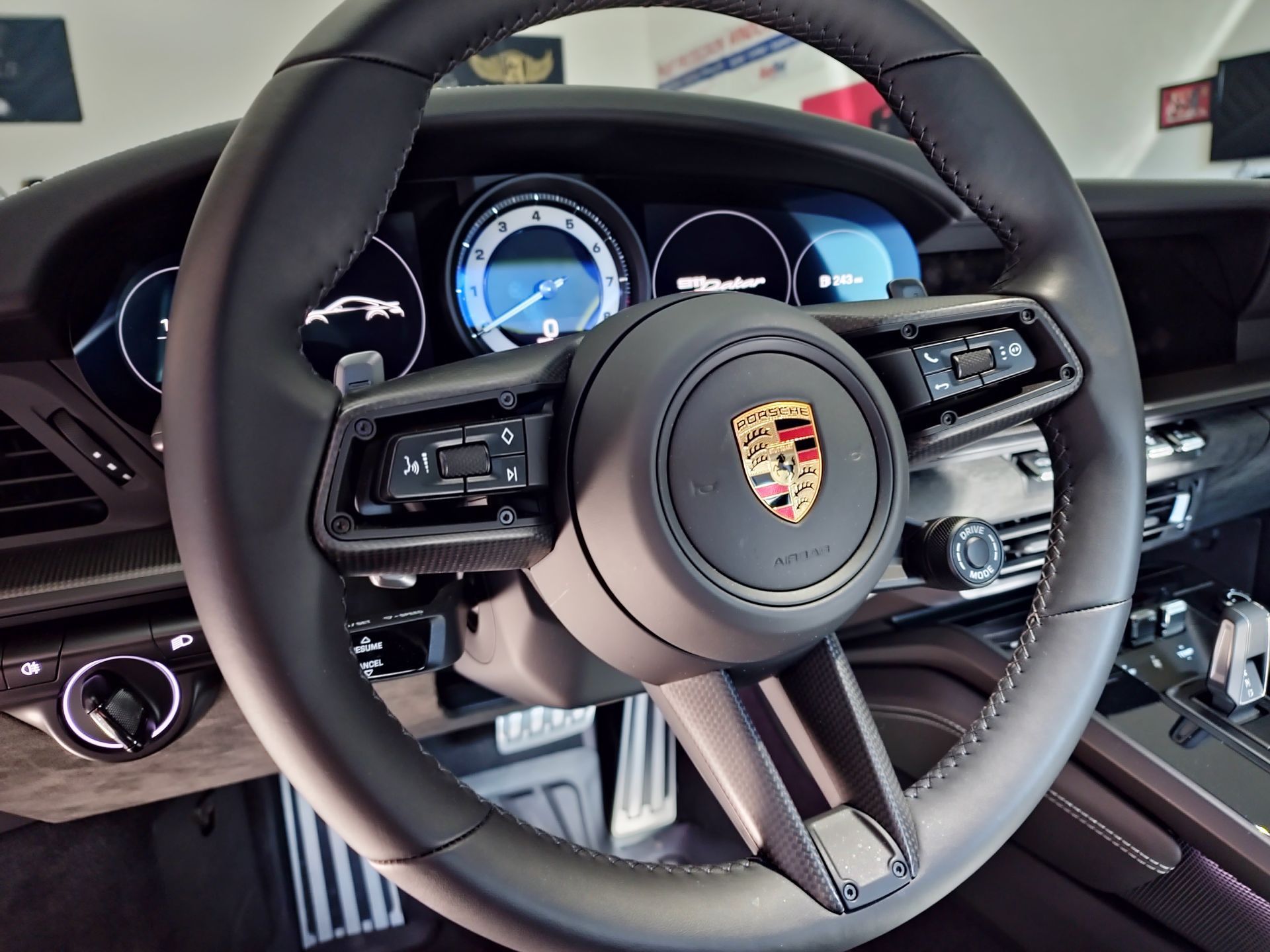 Interior of a Porsche with black steering wheel, digital gauges, and center console visible