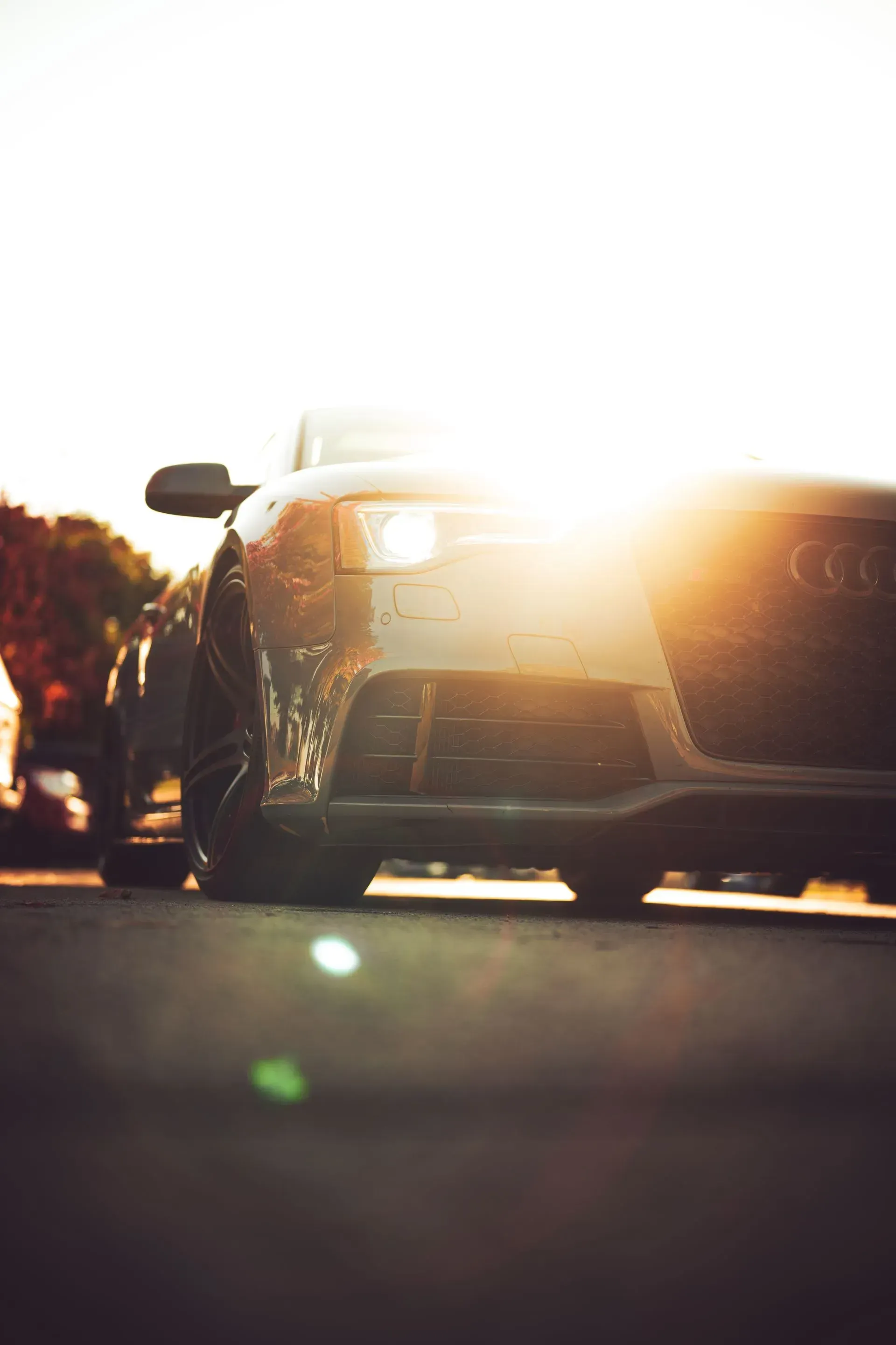 Cars on a road at sunset with bright sun glare and silhouettes of people nearby