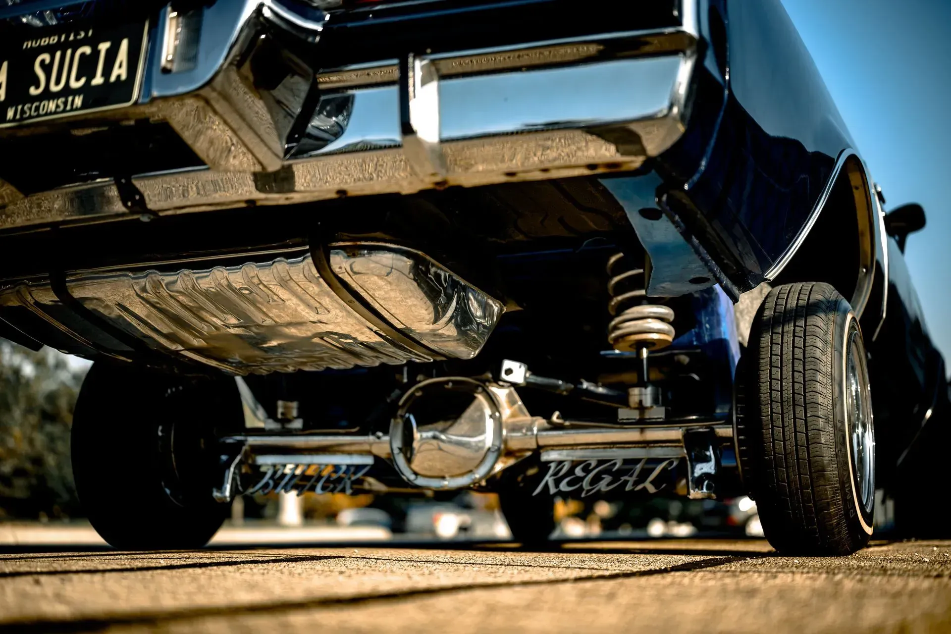 Low-angle view of a black classic car with chrome details on a dirt road