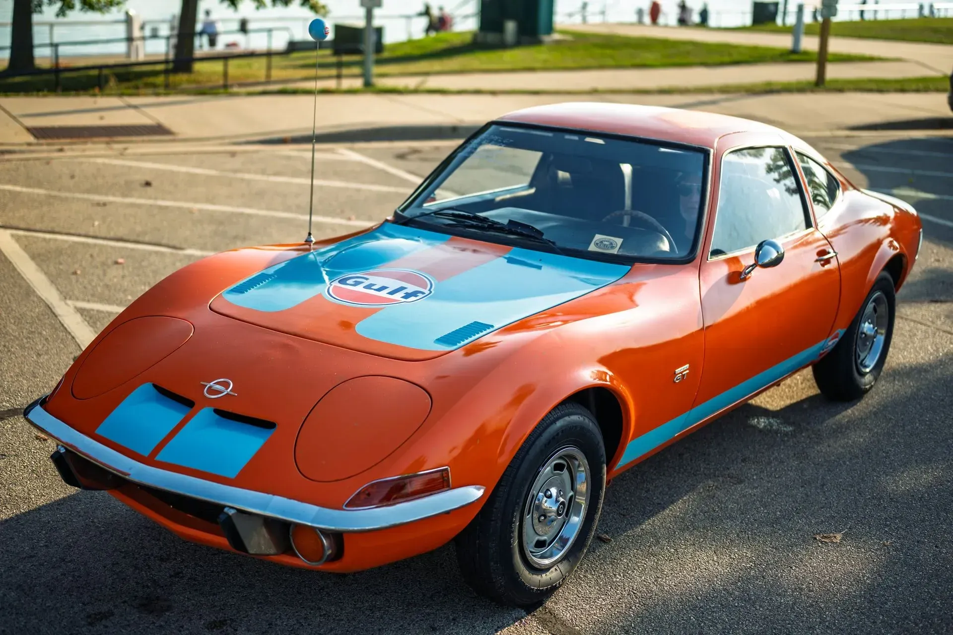 Orange and blue vintage sports car parked on a sunlit street near the waterfront