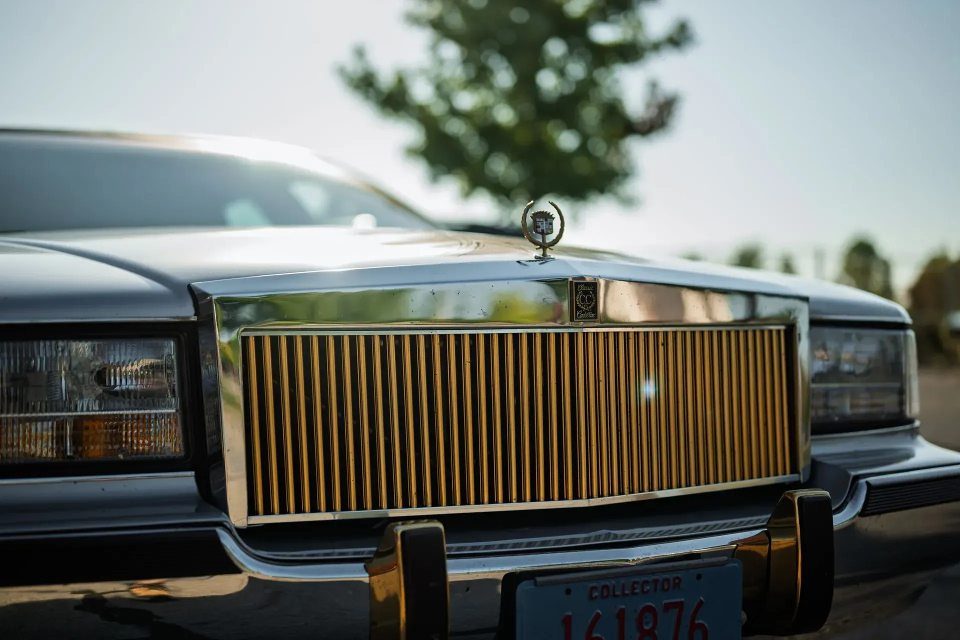Front view of a classic black car with a gold grille and hood ornament outdoors.
