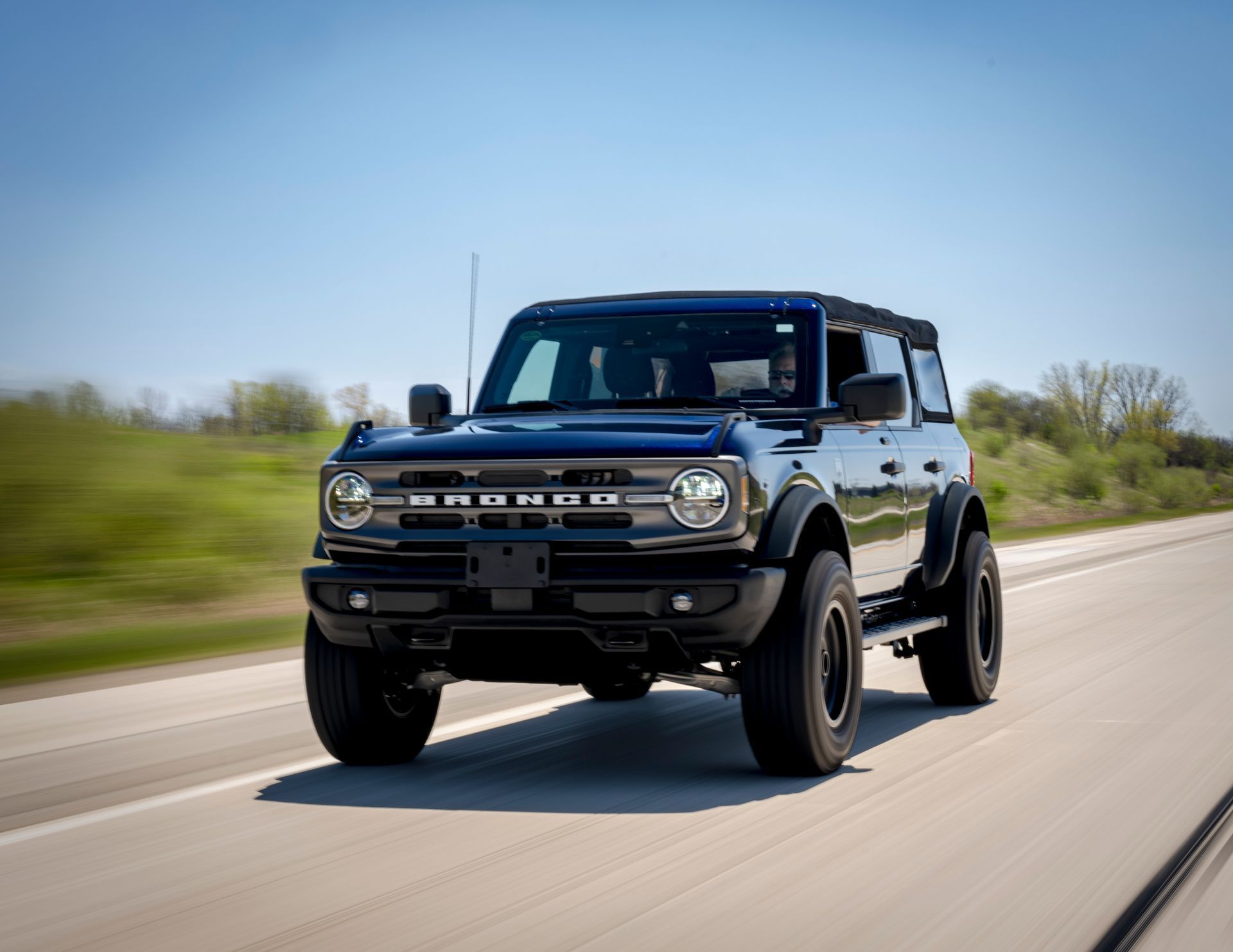 Black off-road SUV driving on a highway under a clear blue sky