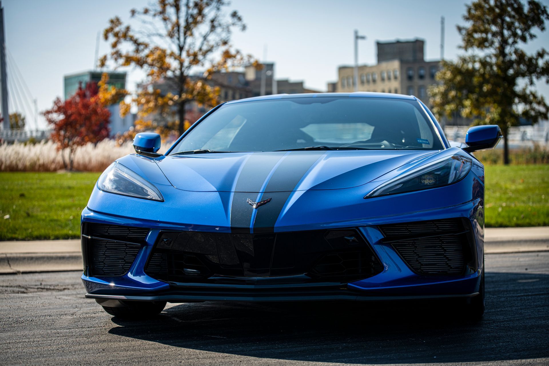 Blue sports car parked outdoors on a sunny day, front view against a blurred background.