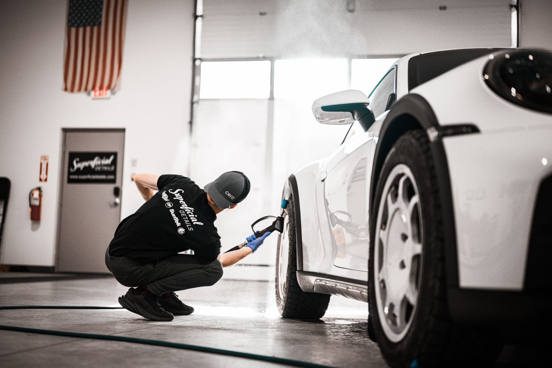 Mechanic polishing a white sports car in a garage