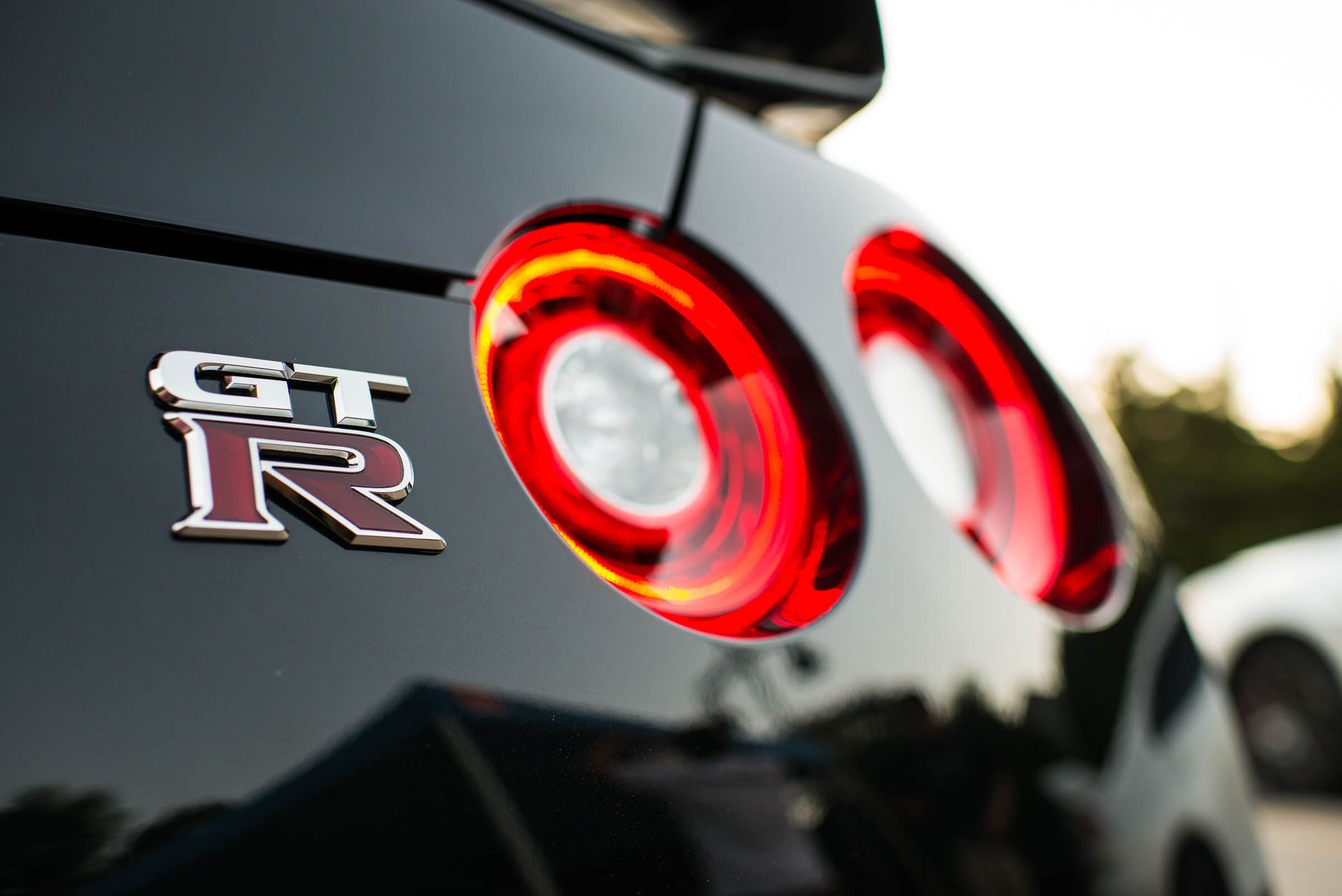 Close-up of a black Nissan GT-R badge and glowing red taillights