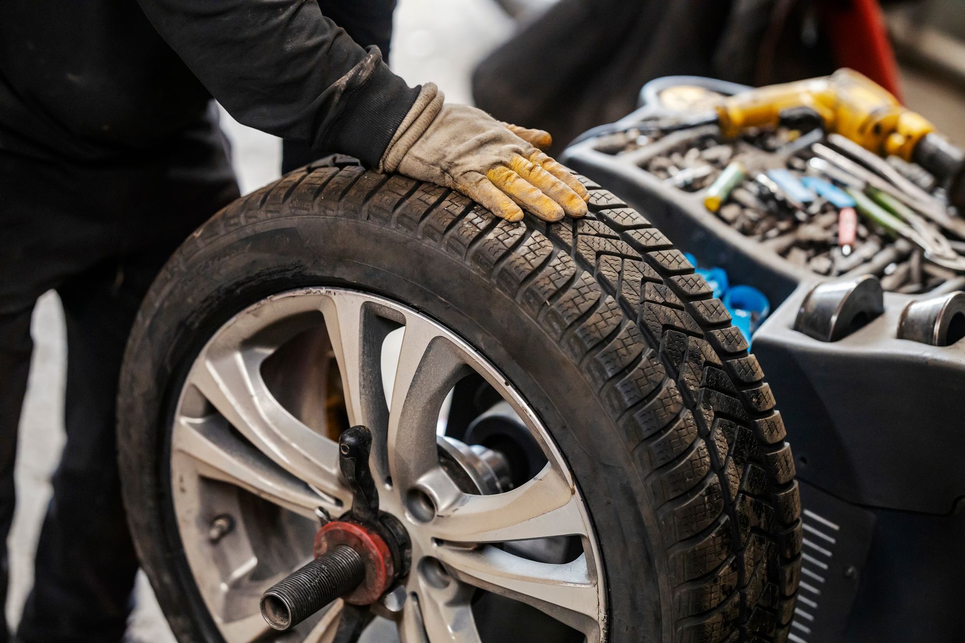 Mechanic installing a tire on a car wheel with tools nearby