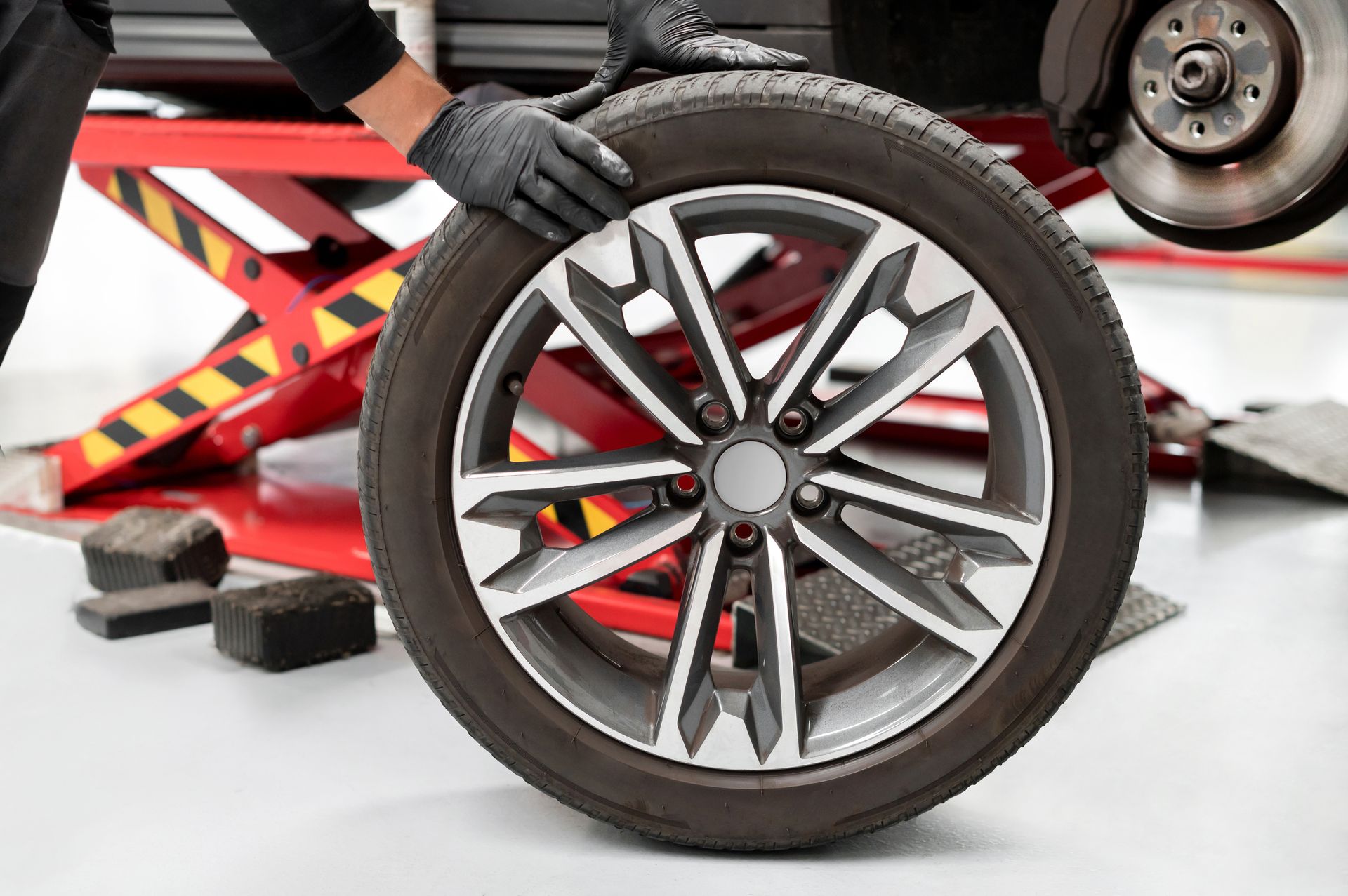 Mechanic’s gloved hand steadying a car wheel during tire service in a garage