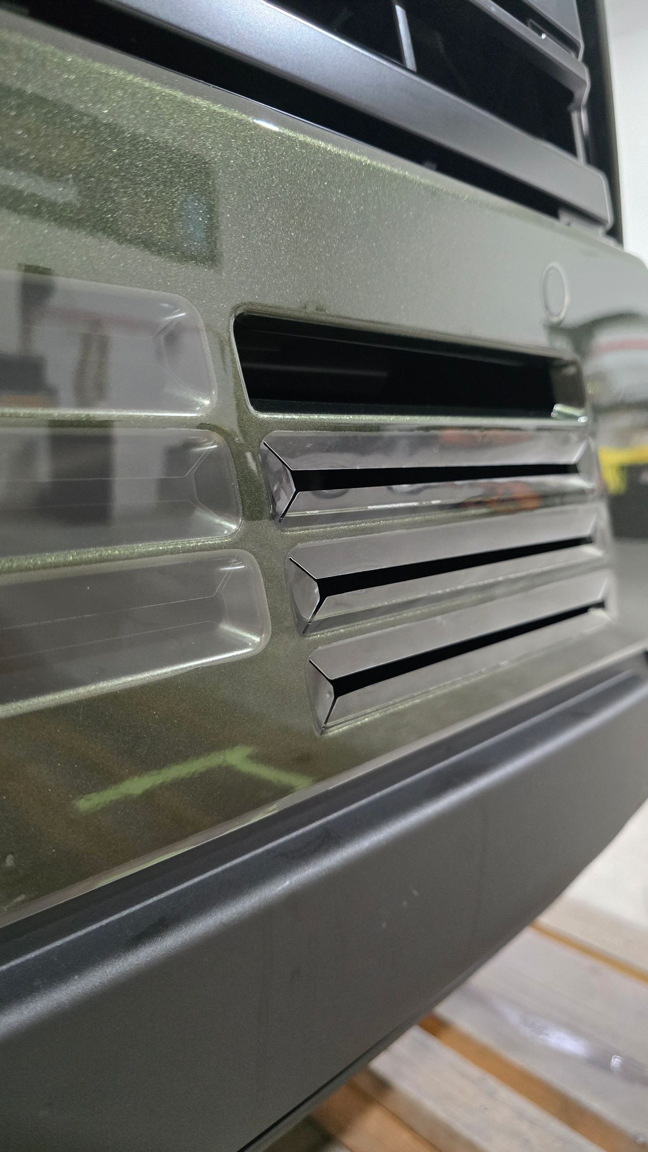 Close-up of a black vented panel with a reflective transparent edge and horizontal slats.