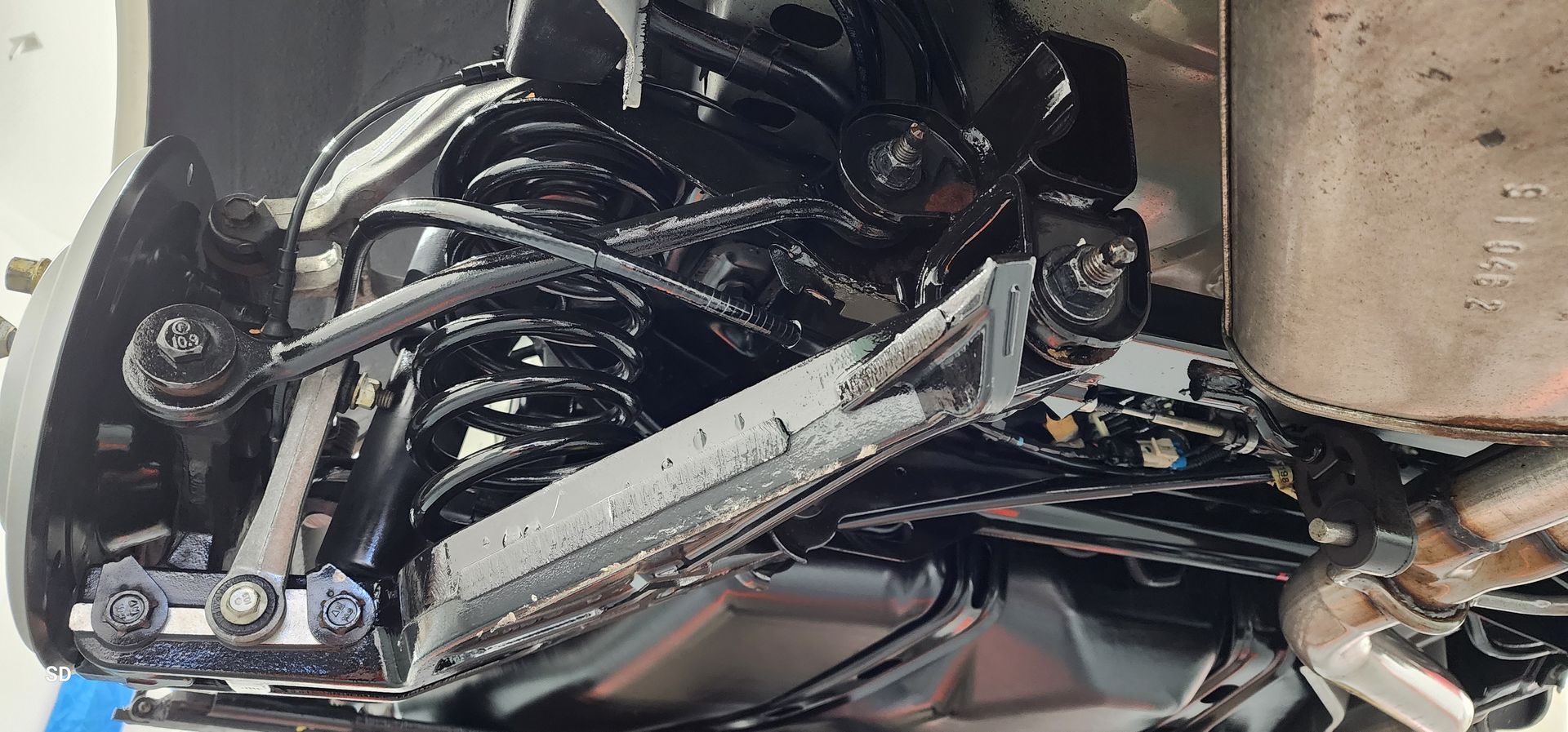 Close-up of a damaged motorcycle front suspension and wheel with exposed black cables and bent metal parts