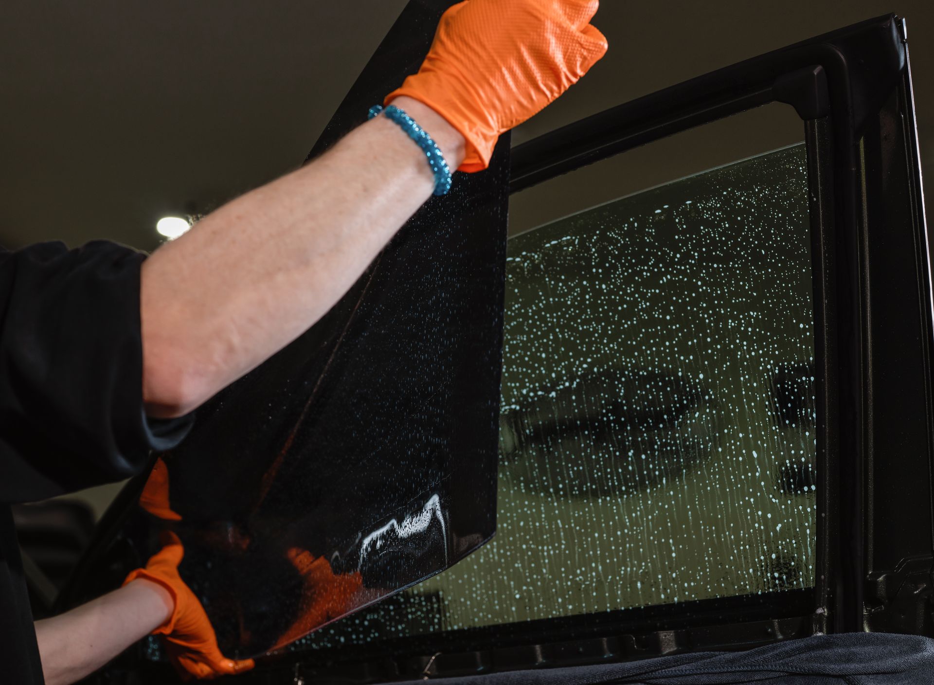 Gloved worker removing shattered car window at night