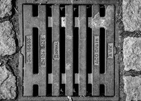 Drainage engineer preparing no-dig drain relining equipment beside an access chamber