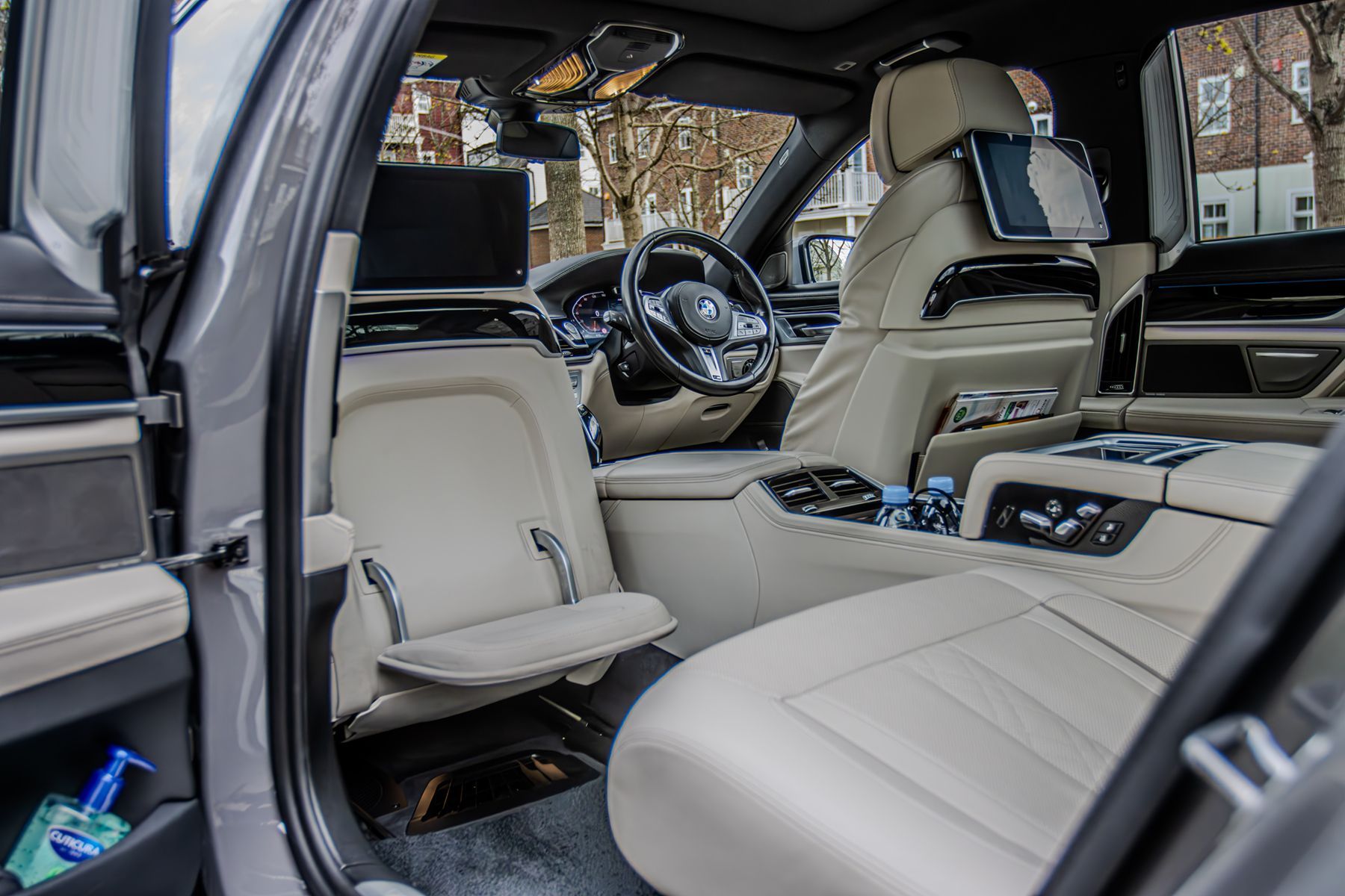 Luxury SUV interior with beige leather seats and open doors, showing the front cabin and rear seating area