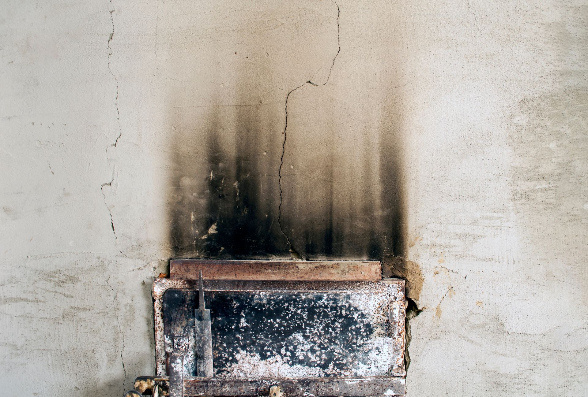 Blackened, soot-stained wall with a small fireplace or vent opening below the stain