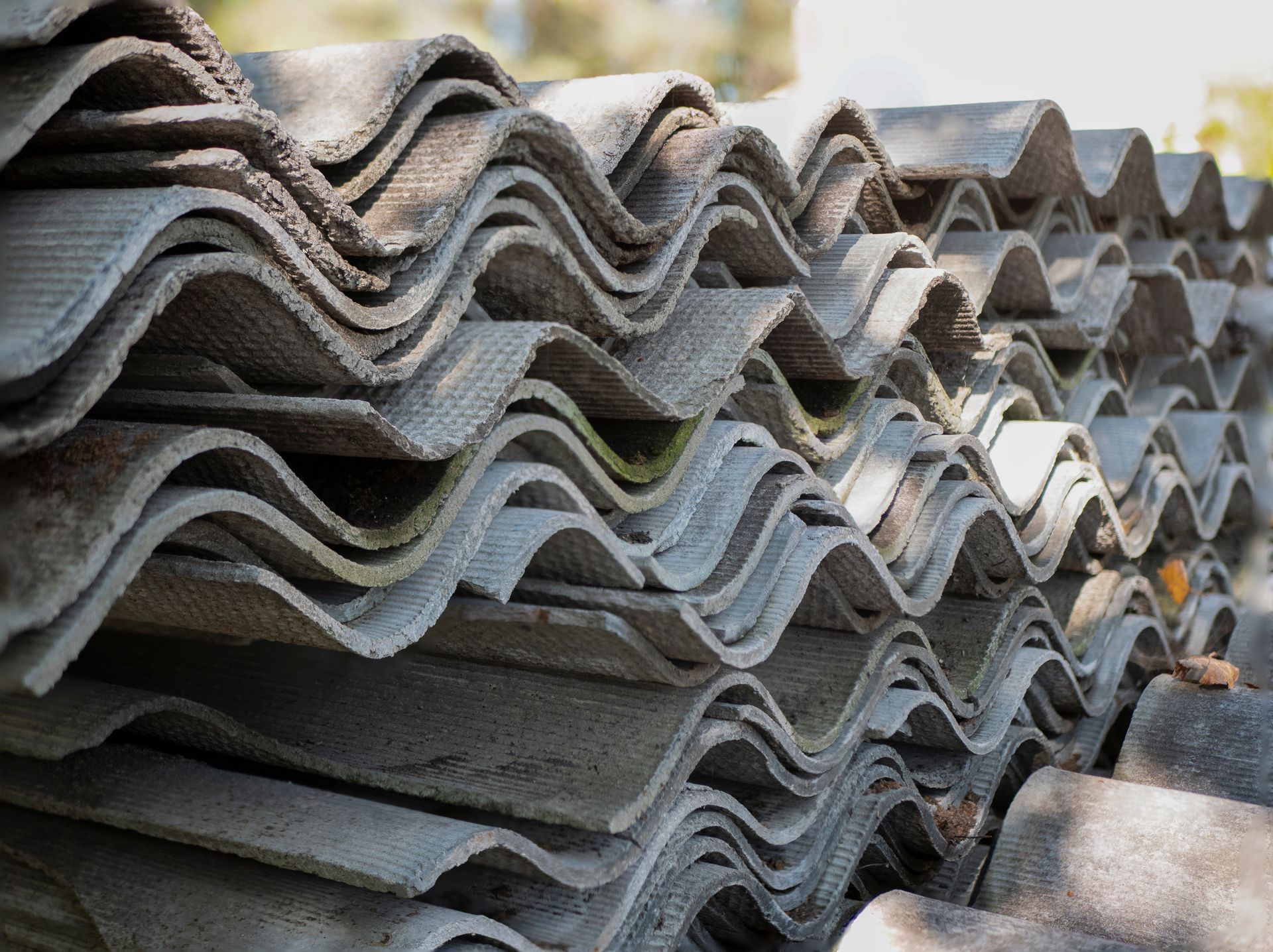 Stacks of gray corrugated roofing sheets piled outdoors in a yard