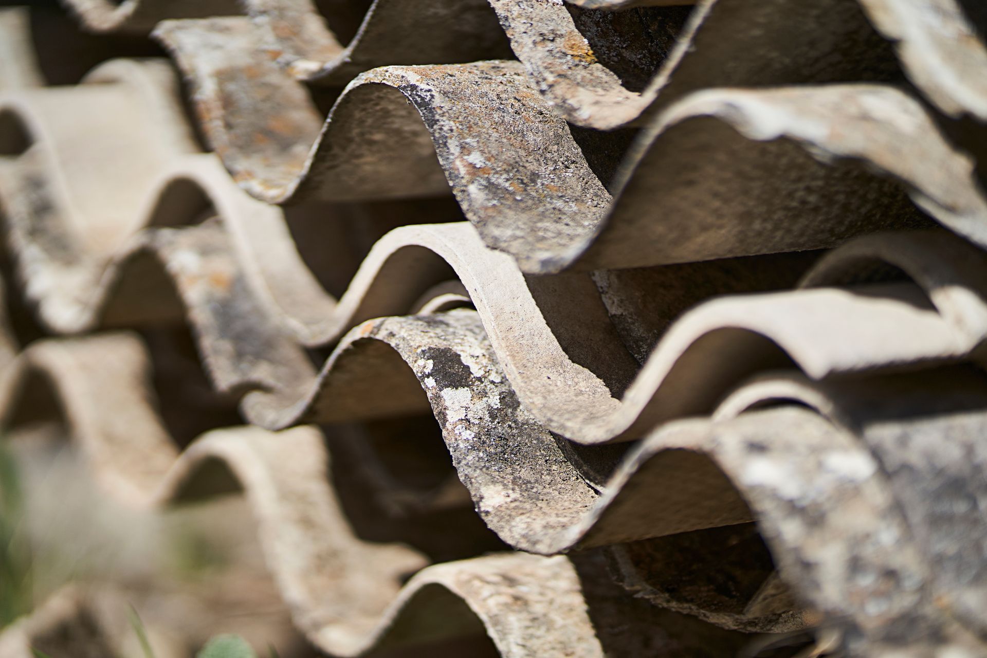 Close-up of stacked, weathered corrugated roofing sheets with wavy ridges