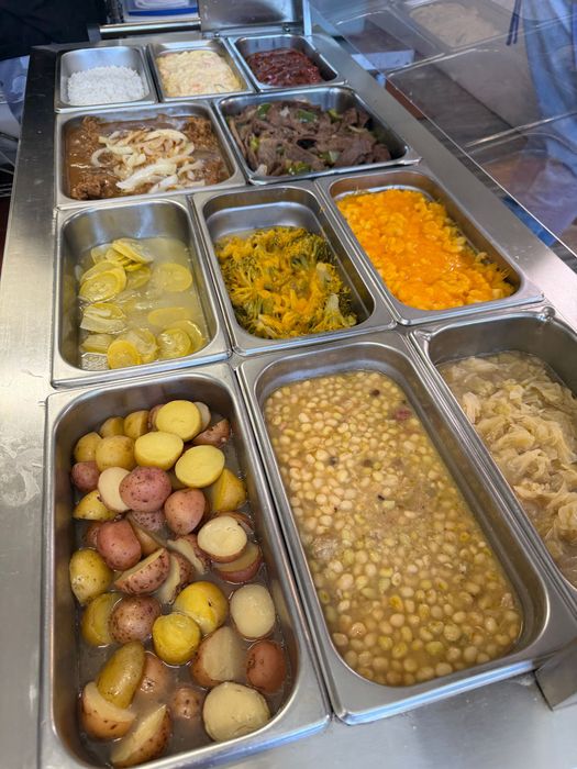 Assorted plated meals with fries, salads, and sandwiches arranged on a dark table.