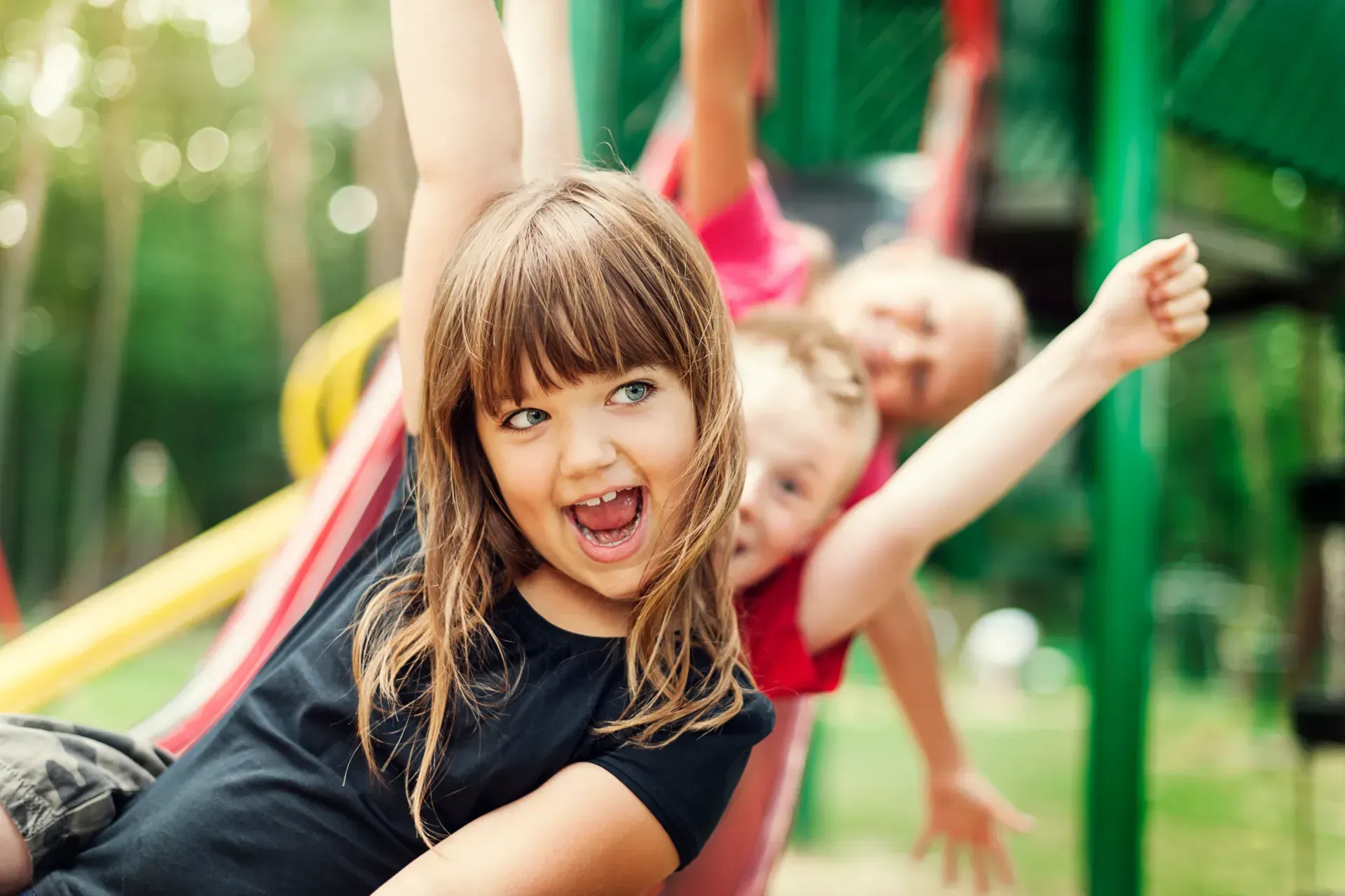 A group of children are playing on a slide at a playground.