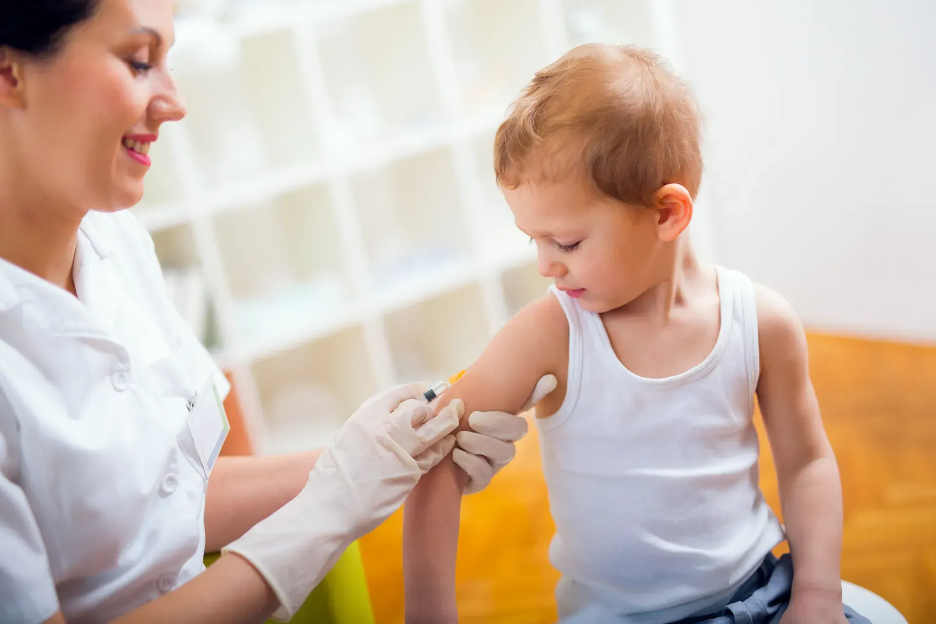 A woman is giving a child an injection in his arm.