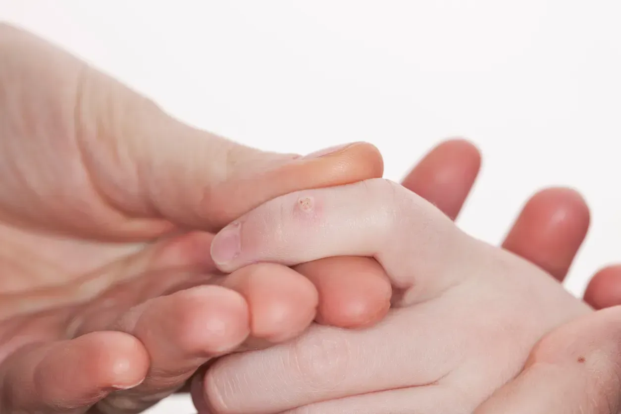A close up of a person holding a child 's hand.
