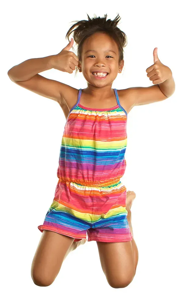 A little girl is jumping in the air and giving a thumbs up.