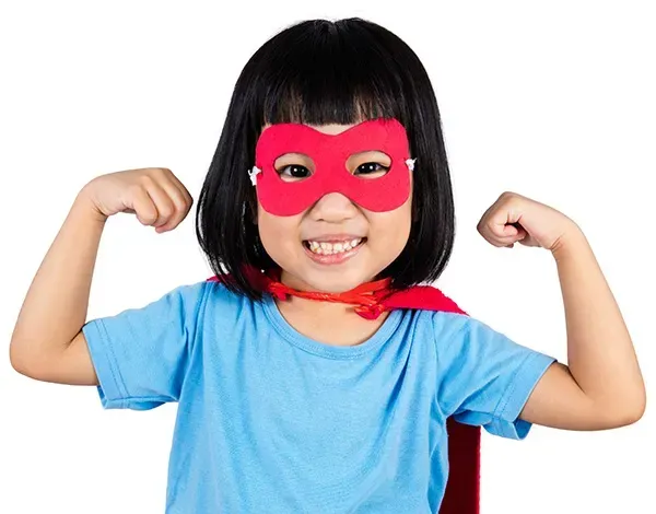 A little girl wearing a red mask and cape is flexing her muscles.