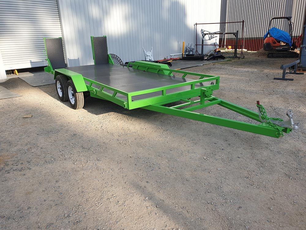 A Green Trailer Is Parked in A Gravel Lot in Front of A Building — ASSB Armidale Sand And Soda Blasting In Armidale, NSW