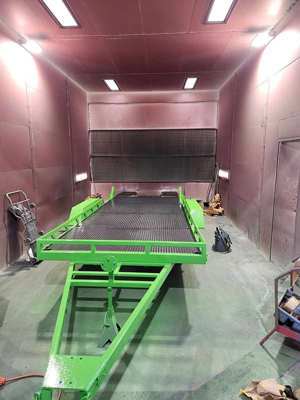 A Green Trailer Is Sitting Inside Of A Paint Booth — ASSB Armidale Sand And Soda Blasting In Armidale, NSW